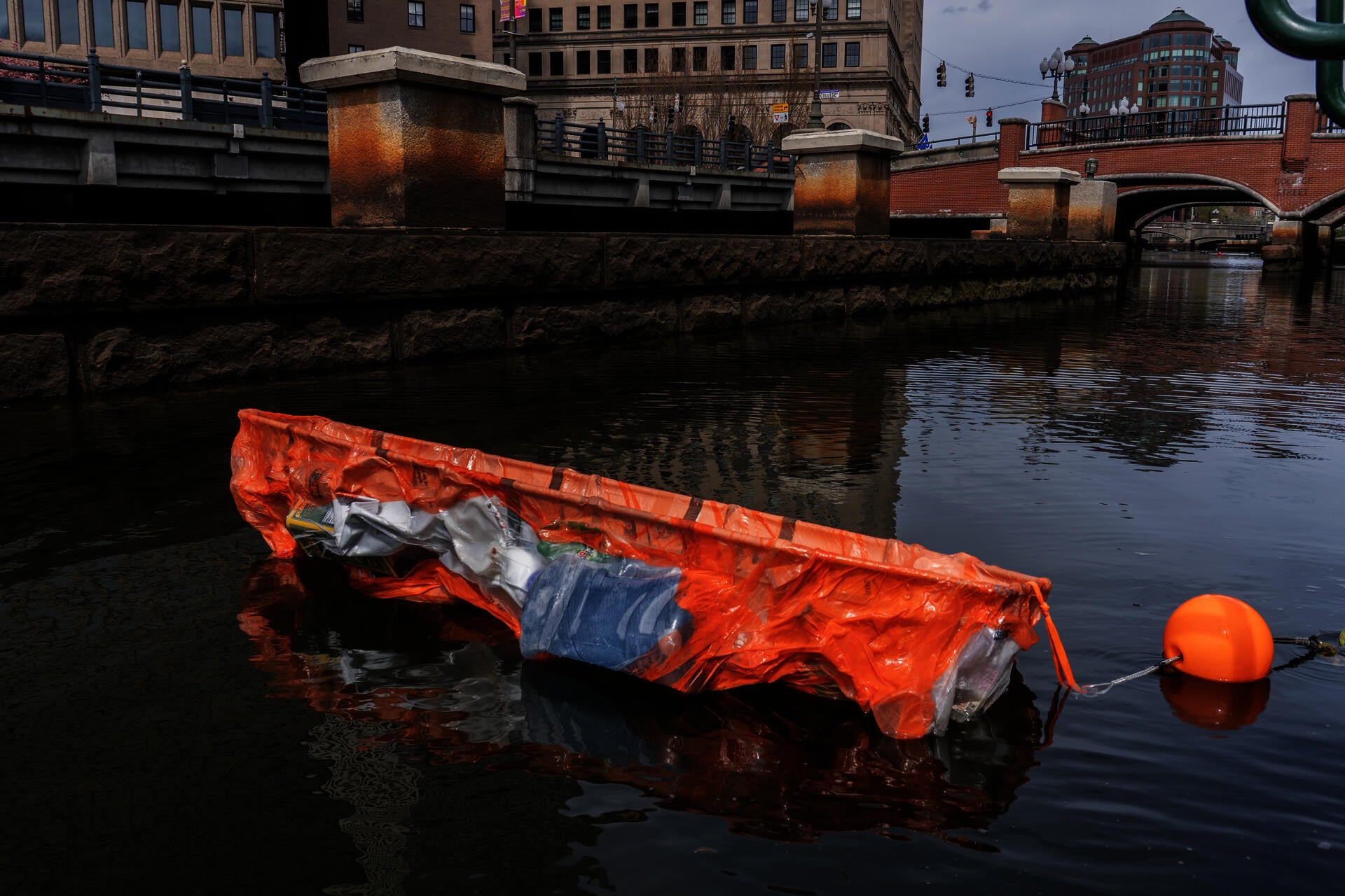 A bright orange stain in the middle of the river. Made from plastic bottles packed into orange plastic bags, vacuum-formed around a rescued bed into a compressed, airtight body. Inside, burned “mummies” made from thin black metal sheets, pressed into my  body.