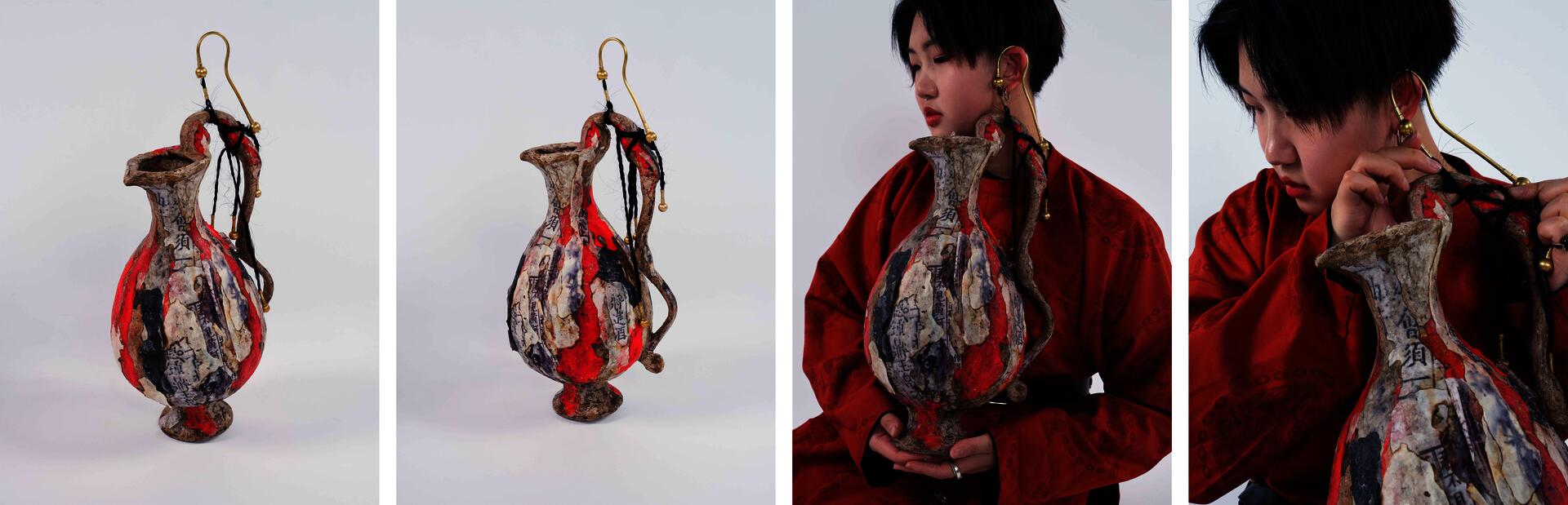  An oversized ear-hanger jewelry piece is suspended from two brass hooks designed to hang from the ears. Braided black hair strands threaded with brass beads connect the hooks to the handle of a large paper mâché wine vessel.