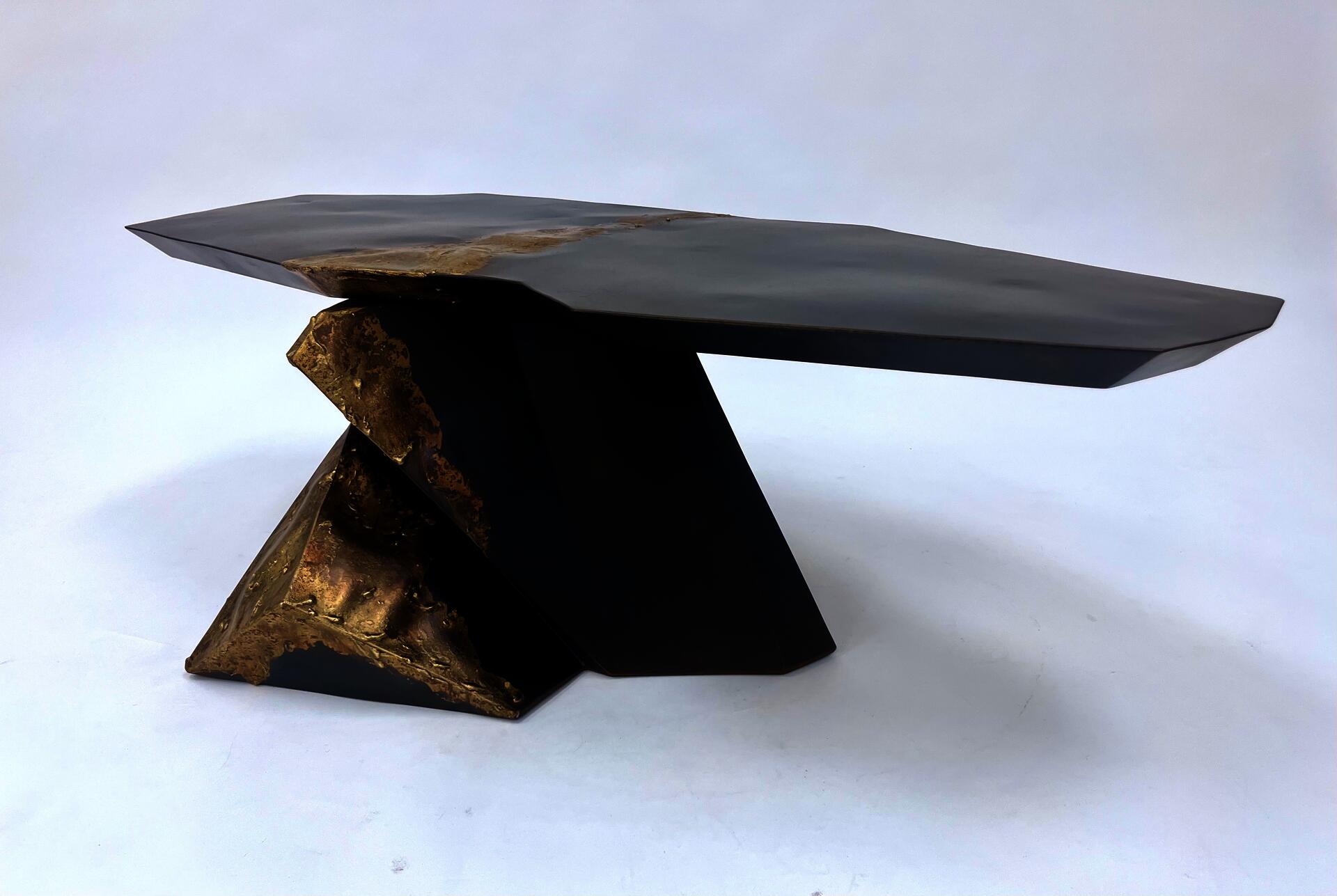 very geometric dark steel base supporting a cantilevered top of dark steel both pieces highlighted by melted bronze that flows through the middle