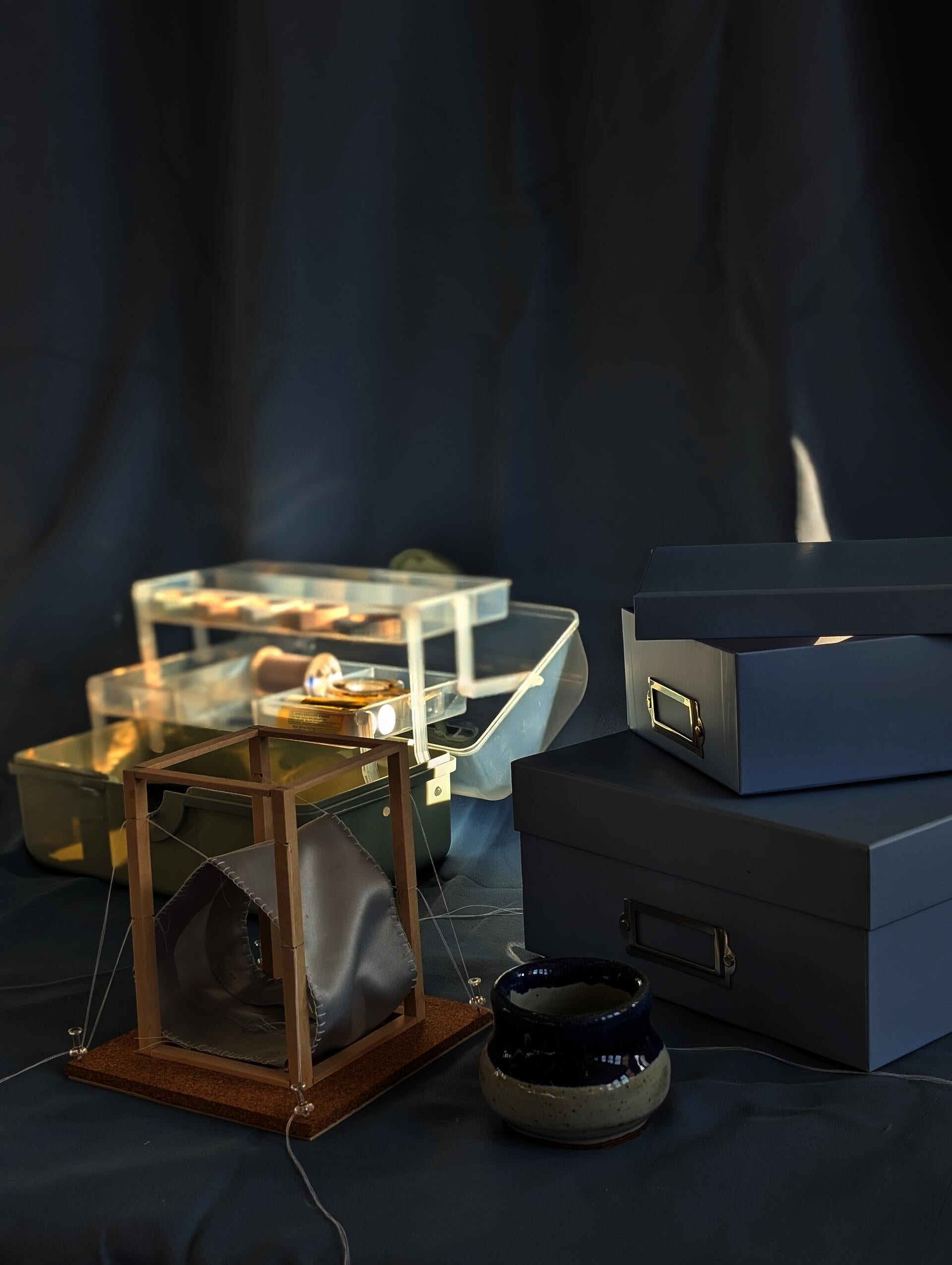A model with a wooden frame in that supports a pulley system attached to a piece of fabric. The string keeps the fabric in tension creating a house-like shape.