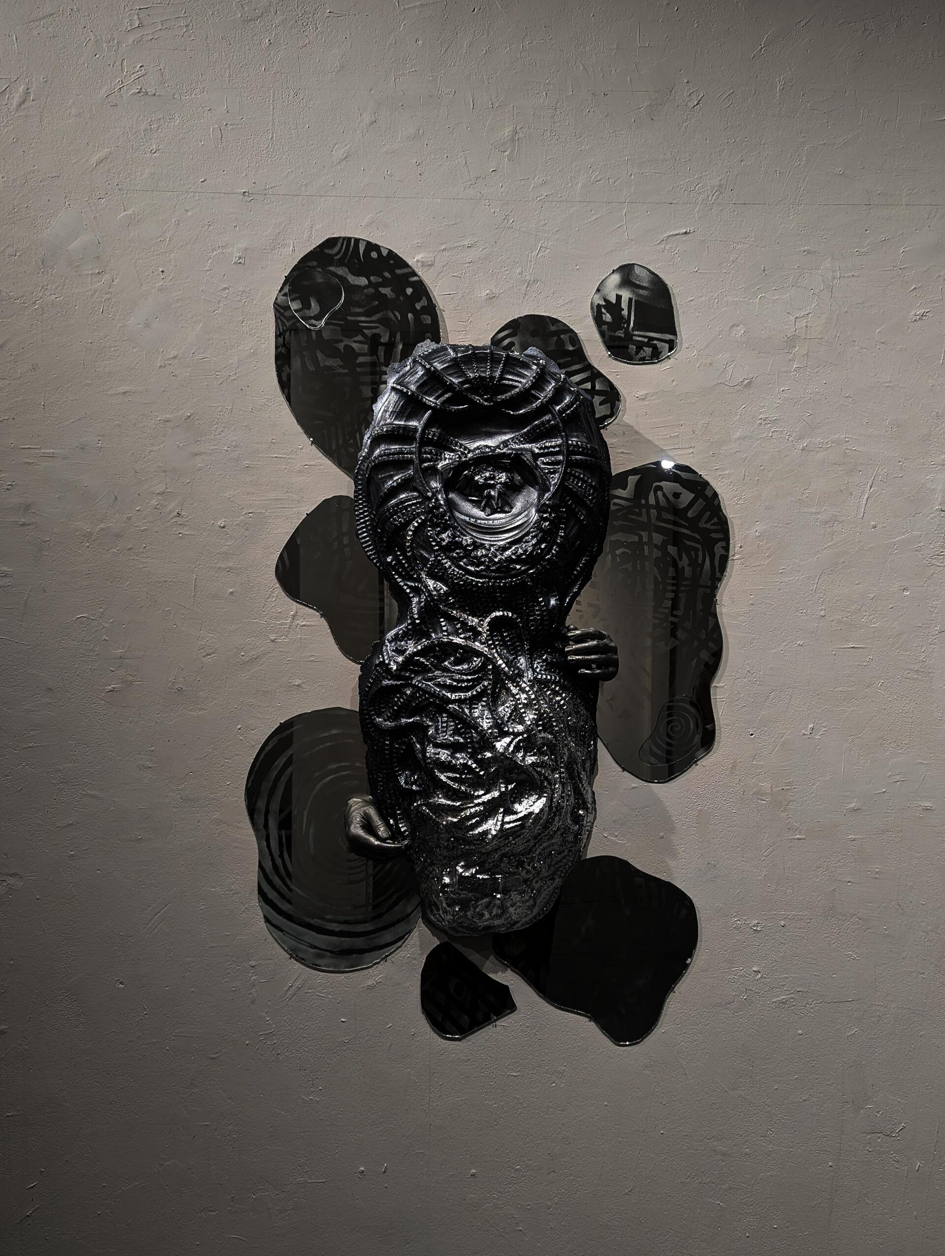 Dried bamboo and metal sculptures with tiny lights hang over a baby banana tree, casting refracted light in a dark room.