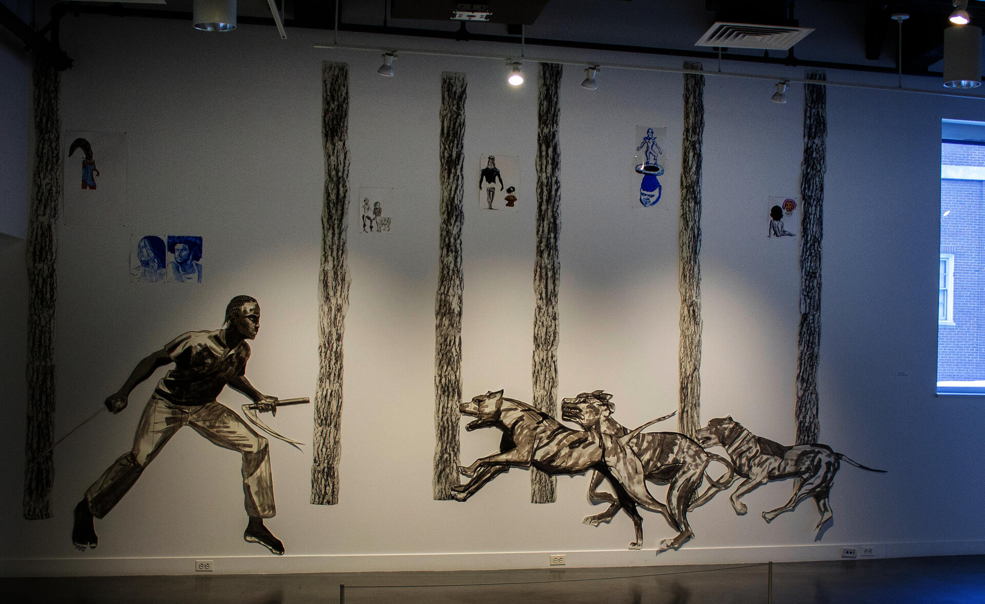 From left to right, a barefoot black figure with cornrows  faces three hounds running towards him in a forest. He has a scythe in each hand, ready to defend himself.