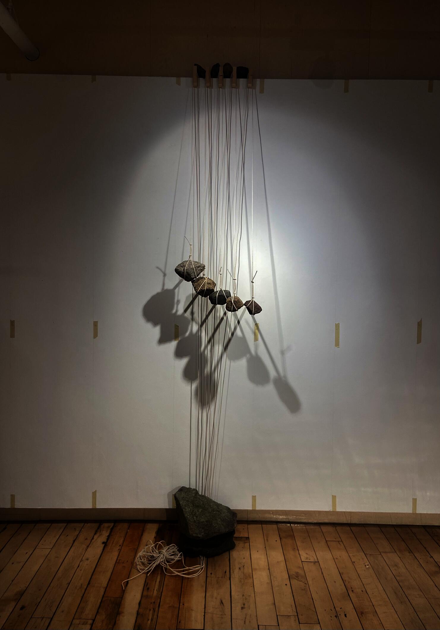 A massive anchor, bracing stones at the top, and hanging rocks are attached with string and hold wood beams in place without fasteners.
