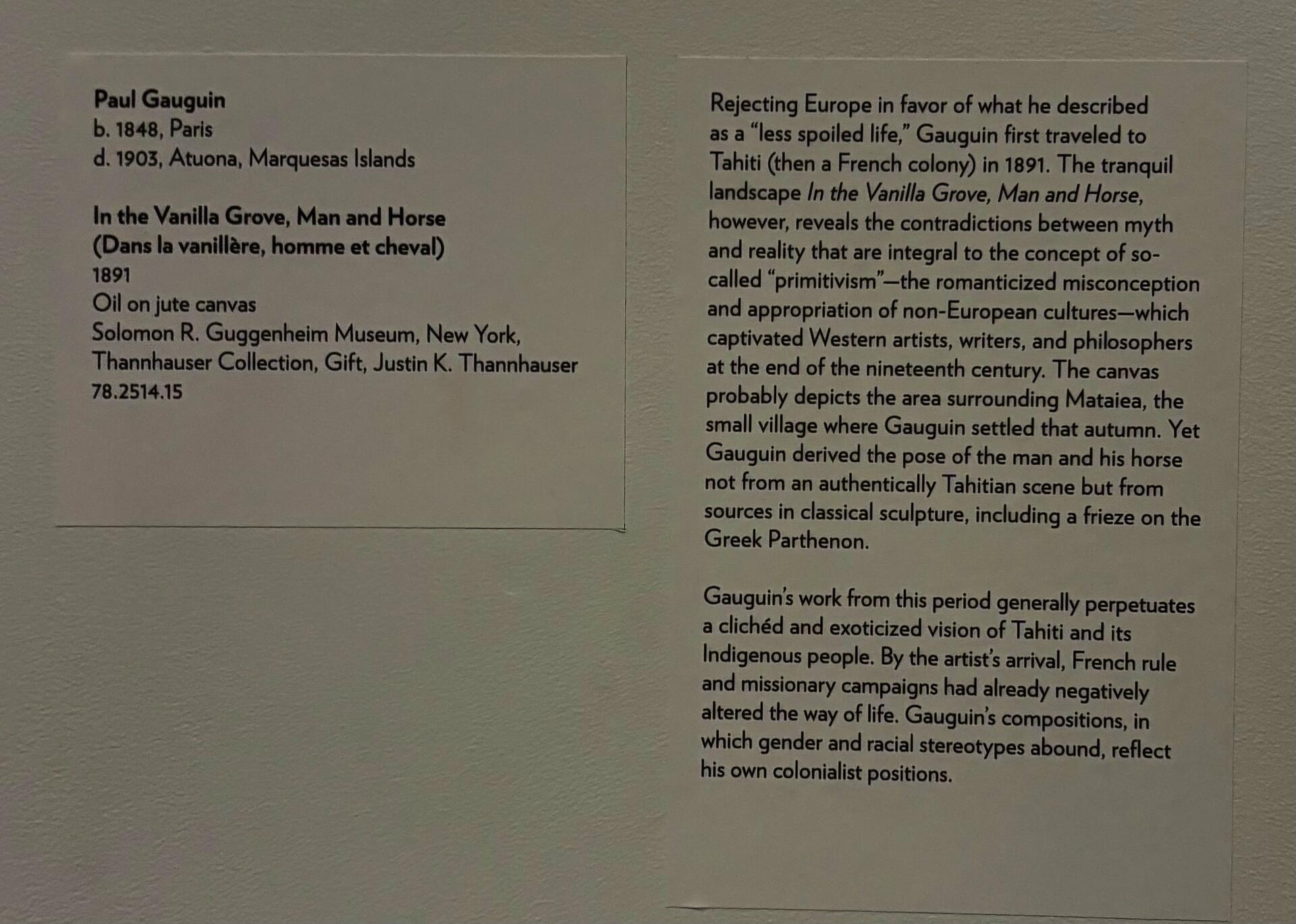 Two rectangular labels affixed to a white wall. The left label lists the artist's name, biographical information, and collection details about the painting. The right label shares a brief interpretive description of Gauguin's travels to Tahiti and exoticizing portrayal of its Indigenous people. 