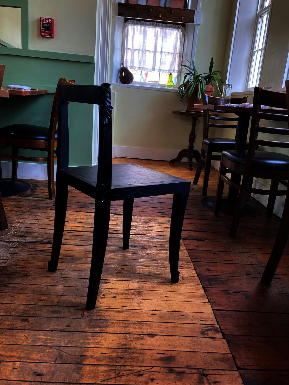 Hand-carved dining chair with clean lines, leather seat, and varying leaf motifs reflecting restaurant’s seasonal food theme.