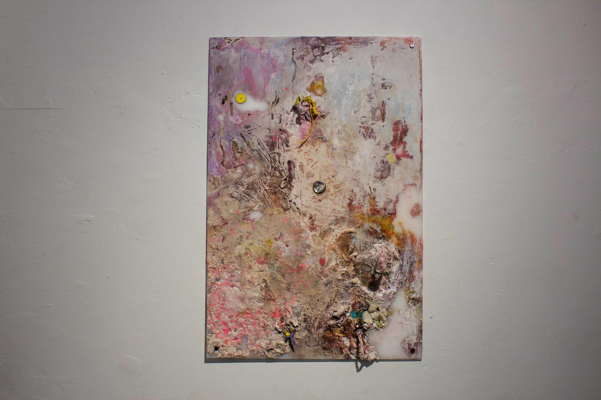 a pink mixed media painting with a metal circle in its center. 