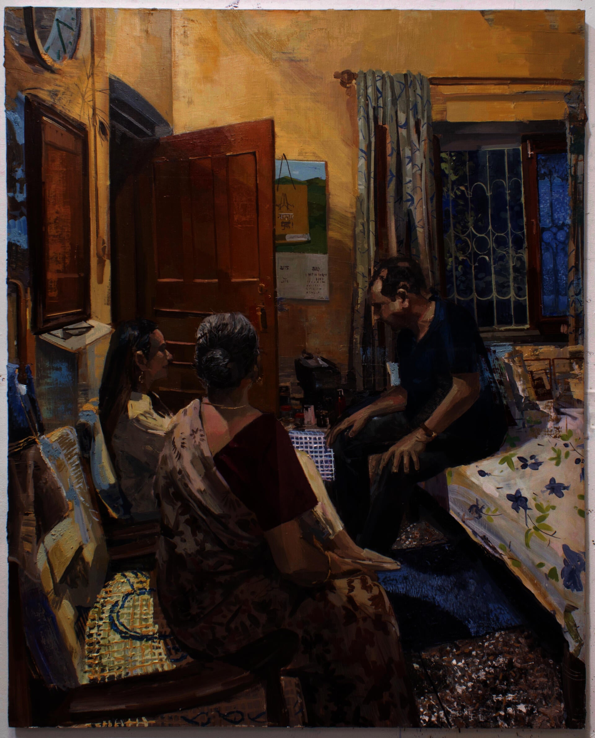 Three figures seated in a room lit with a warm yellow light. 