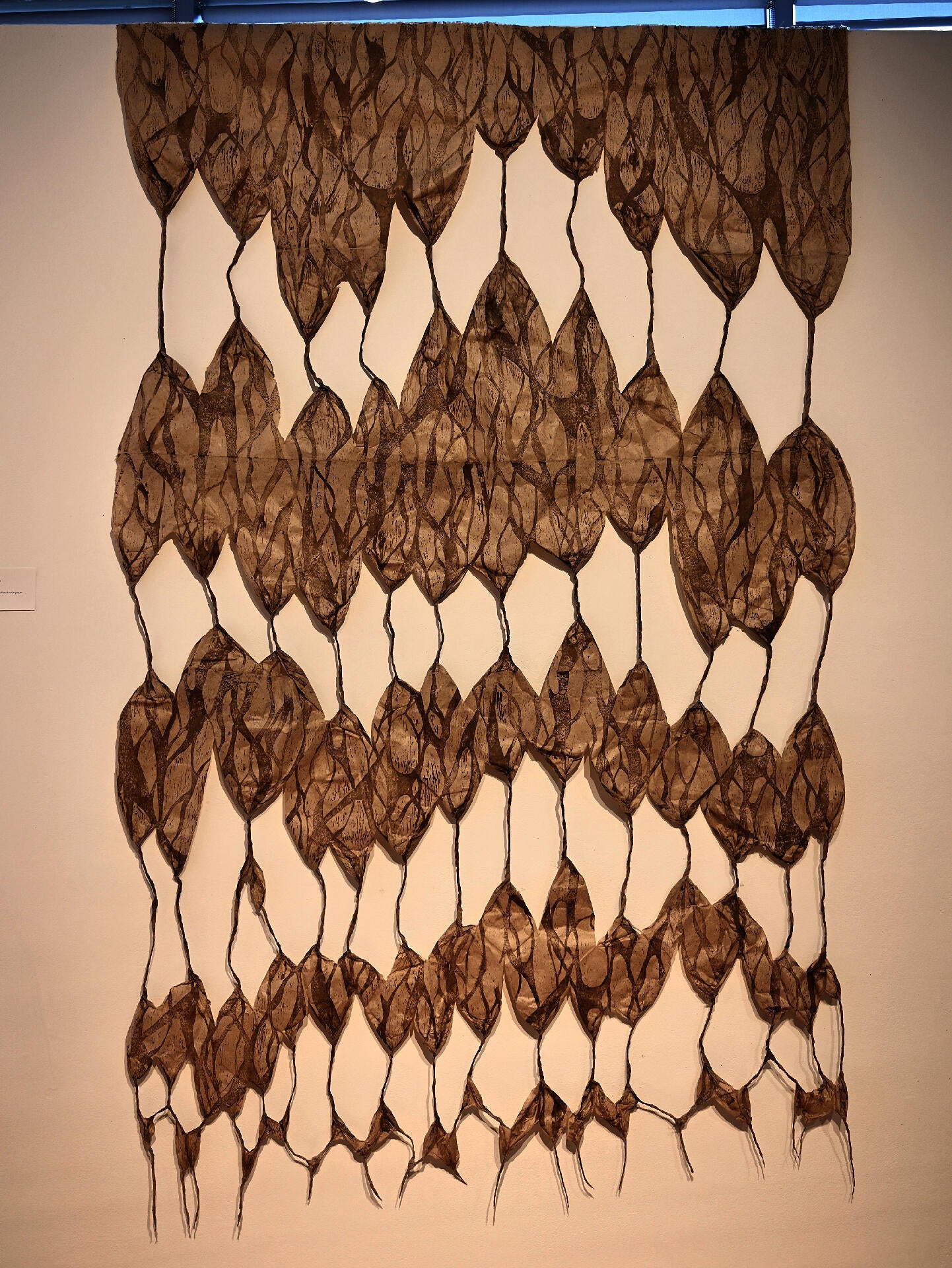 Layered handmade paper print with web-like forms and mycelium patterns connected by twisted paper strands.