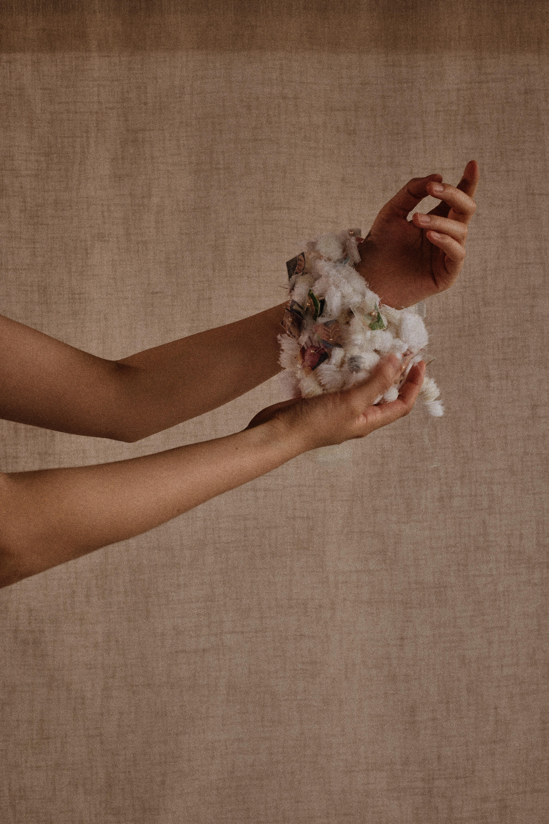 hands holding a delicately sewn together clump of fabric