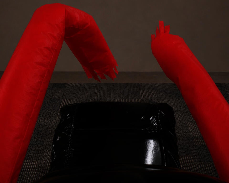 POV shot of the CHAIR FOR WORKPLACE MORALE with a vinyl inflatable office chair seat and red inflatable tube arms swinging side to side.