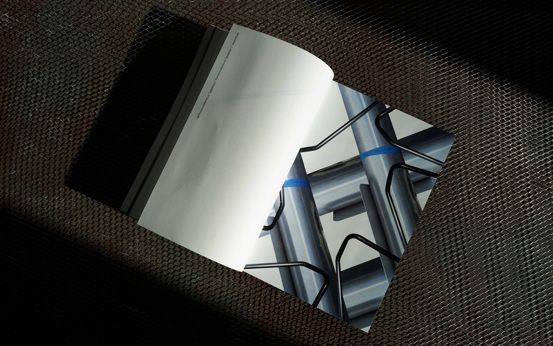 An open magazine spread laid on an expanded metal mesh surface in raking light.