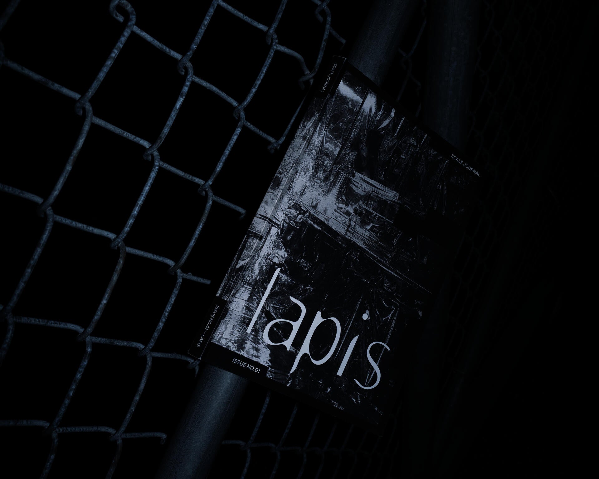 Publication copy resting against a chain-link fence.