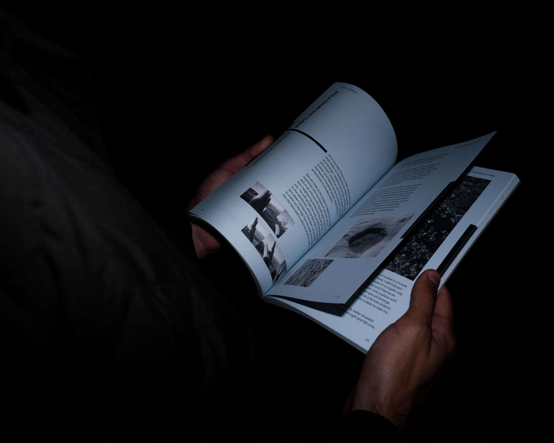 A person's hands holding an open copy of Scale Journal in a dark setting. The visible spread shows black-and-white photographs alongside body text under the section heading "It's a Courtesy Thing."