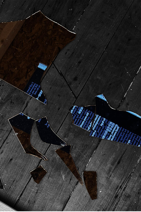 Scattered shards of a broken mirror lying on a worn wooden floor. The jagged, reflective pieces capture fragmented images of two distinct surfaces: dense white text on a dark background and the rough texture of oriented strand board (OSB).