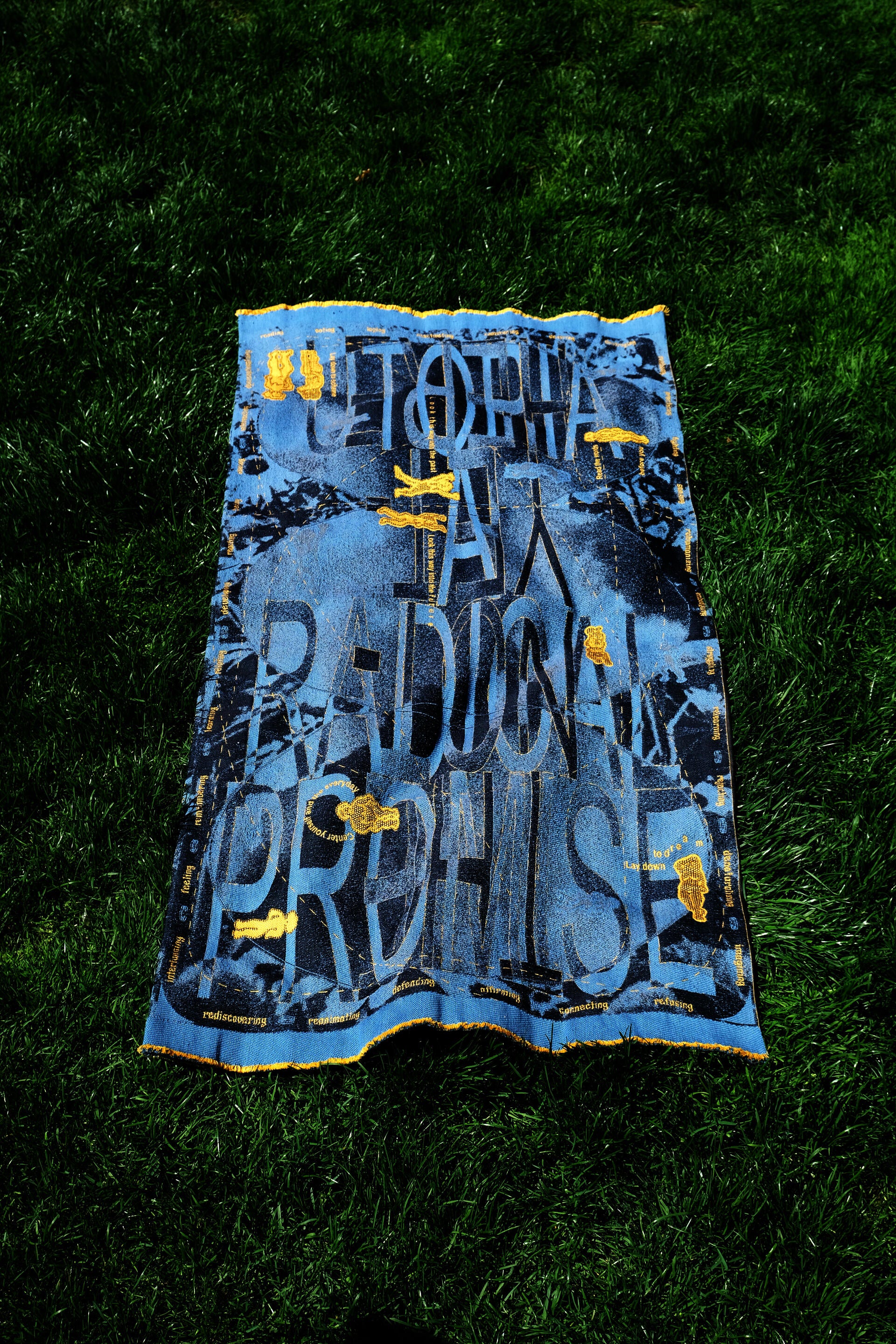 A blue and yellow-gold typographic textile on grass