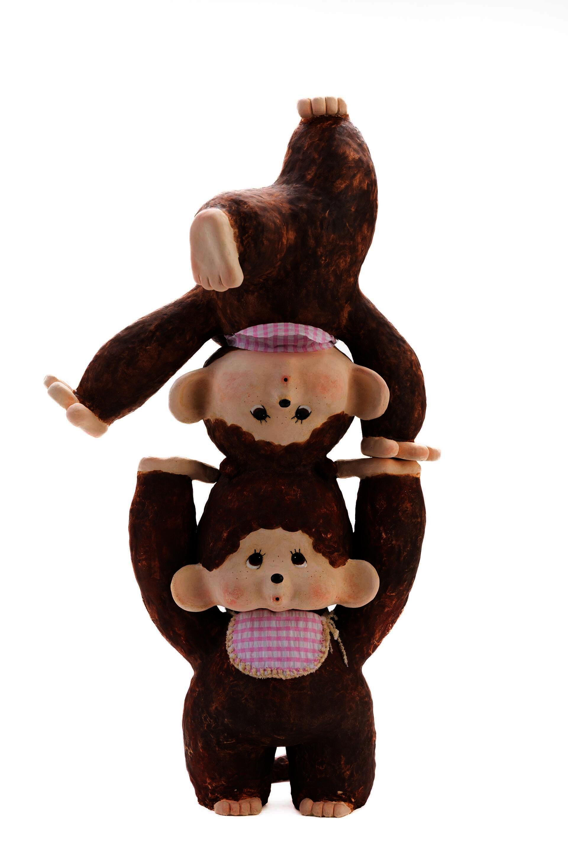 Two enlarged Monchhichi toy stacking on each other with fabrics on them. 