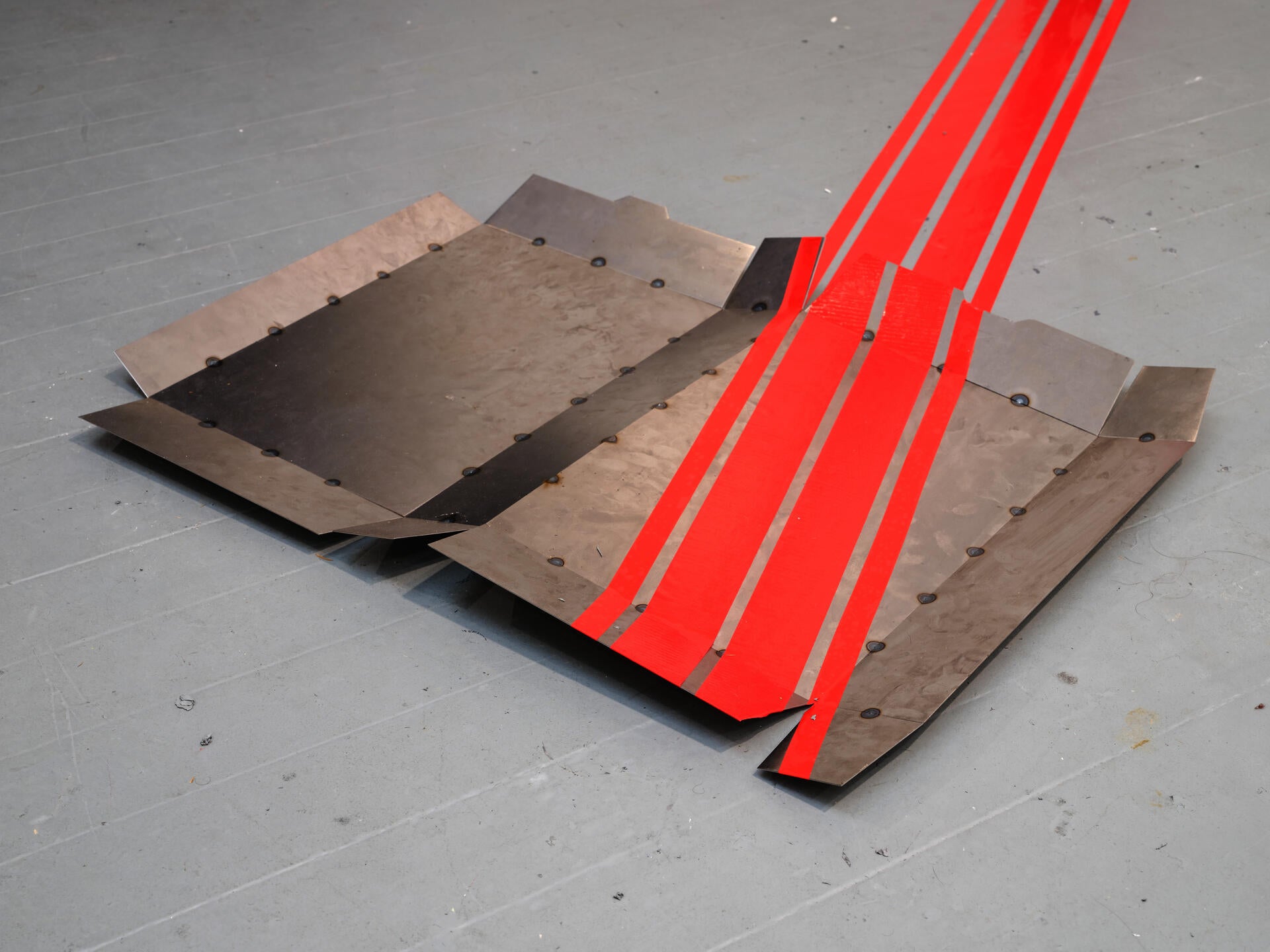 An open steel cereal box with four red stripes lies open on the floor.