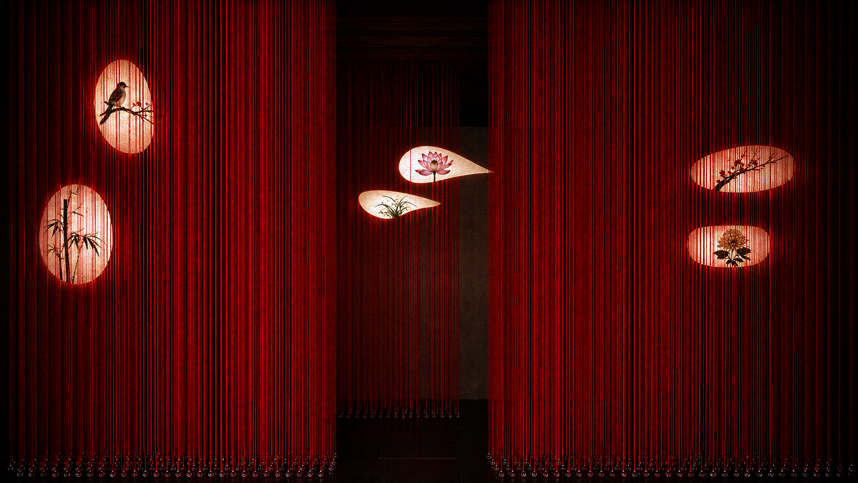 Immersive dense red silk threads hang like layered curtains, while revealing suspended glowing lamps with Chinese traditional embroidery of birds and flowers.