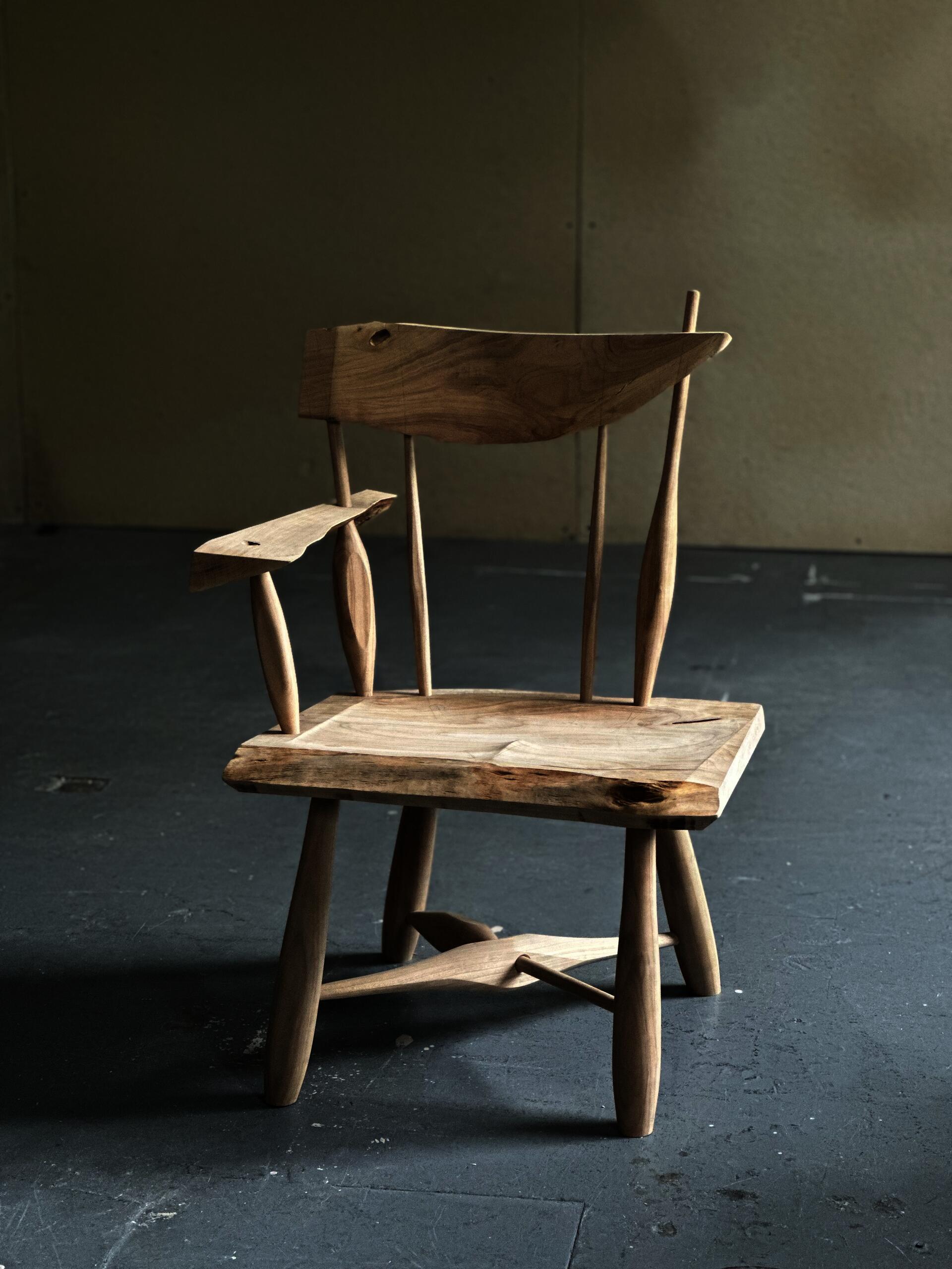 Windsor-inspired cherry chair made from a single salvaged board, featuring sculpted spindles, live edges, and visible knots. The chair emphasizes material continuity, irregularity, and the relationship between natural growth, structure, and hand-shaped form.
