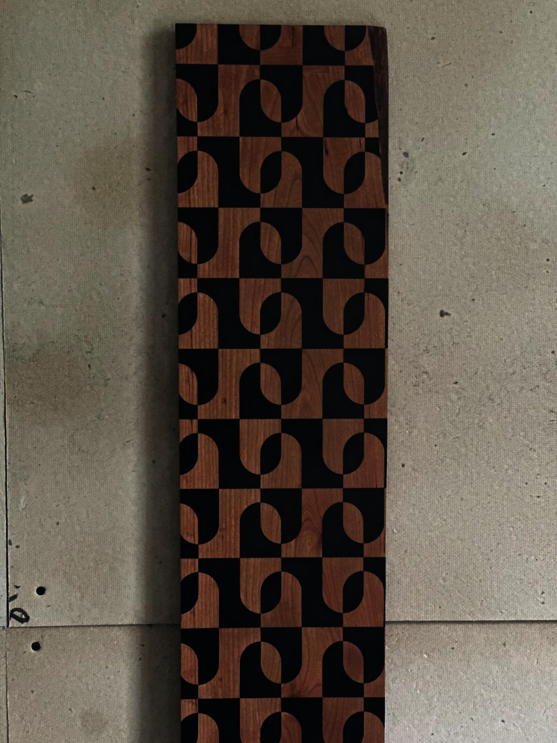 Cherry wood growth chart with a geometric pattern created through masked black vinyl mounted to the wood. 
