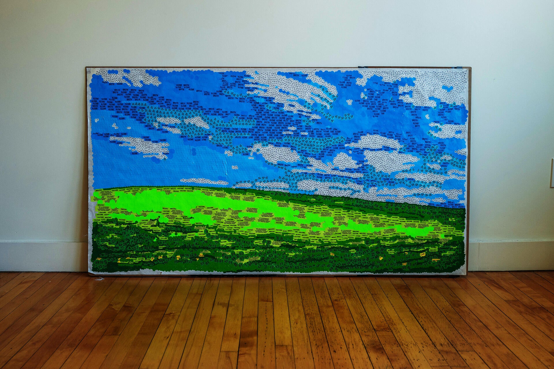 A mosaic landscape assembled from thousands of repurposed stickers — hazard warnings, food labels, confidentiality markers — evoking pointillism. From afar, nature; up close, the symbols of automated consumption.