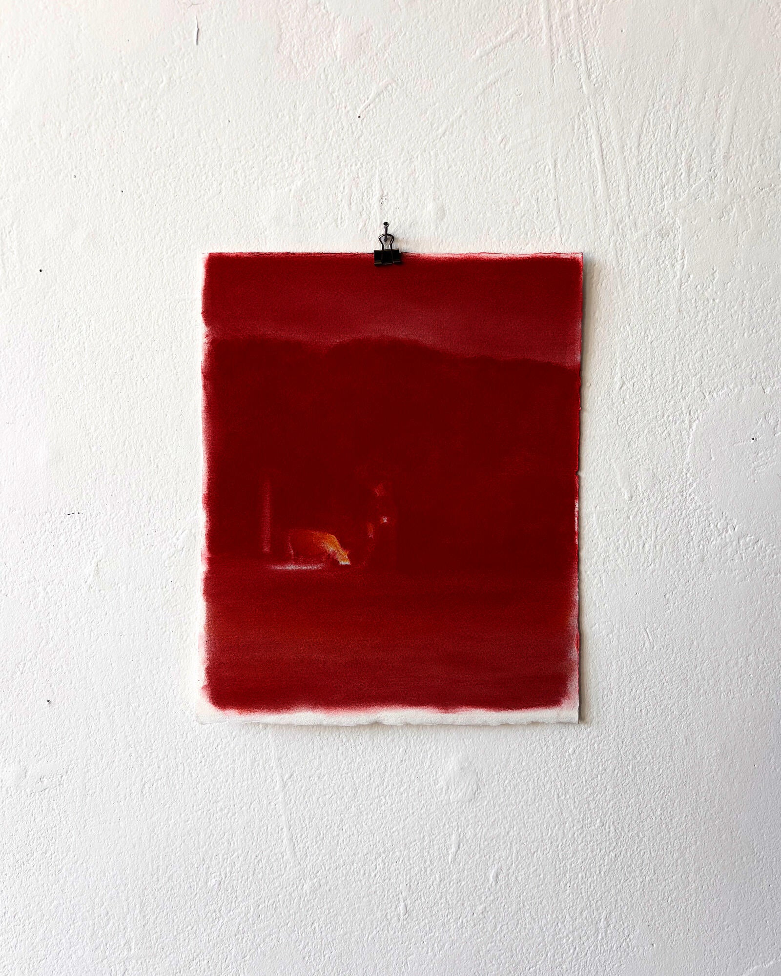A piece of paper is covered with bright red chalk pastel. It is so red it almost glows. 