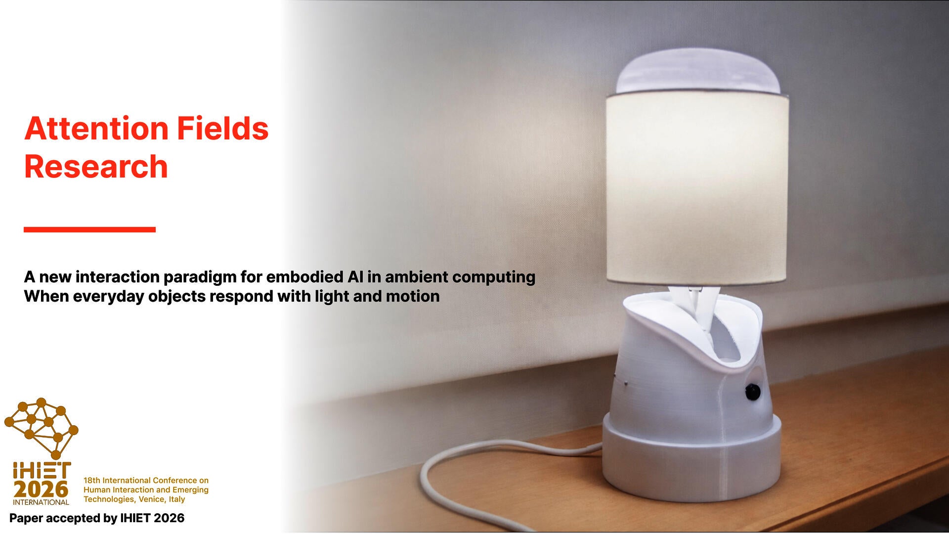 White interactive lamp prototype with a cylindrical fabric shade displayed on a wooden surface against a soft neutral background, representing embodied AI and ambient interaction research.
