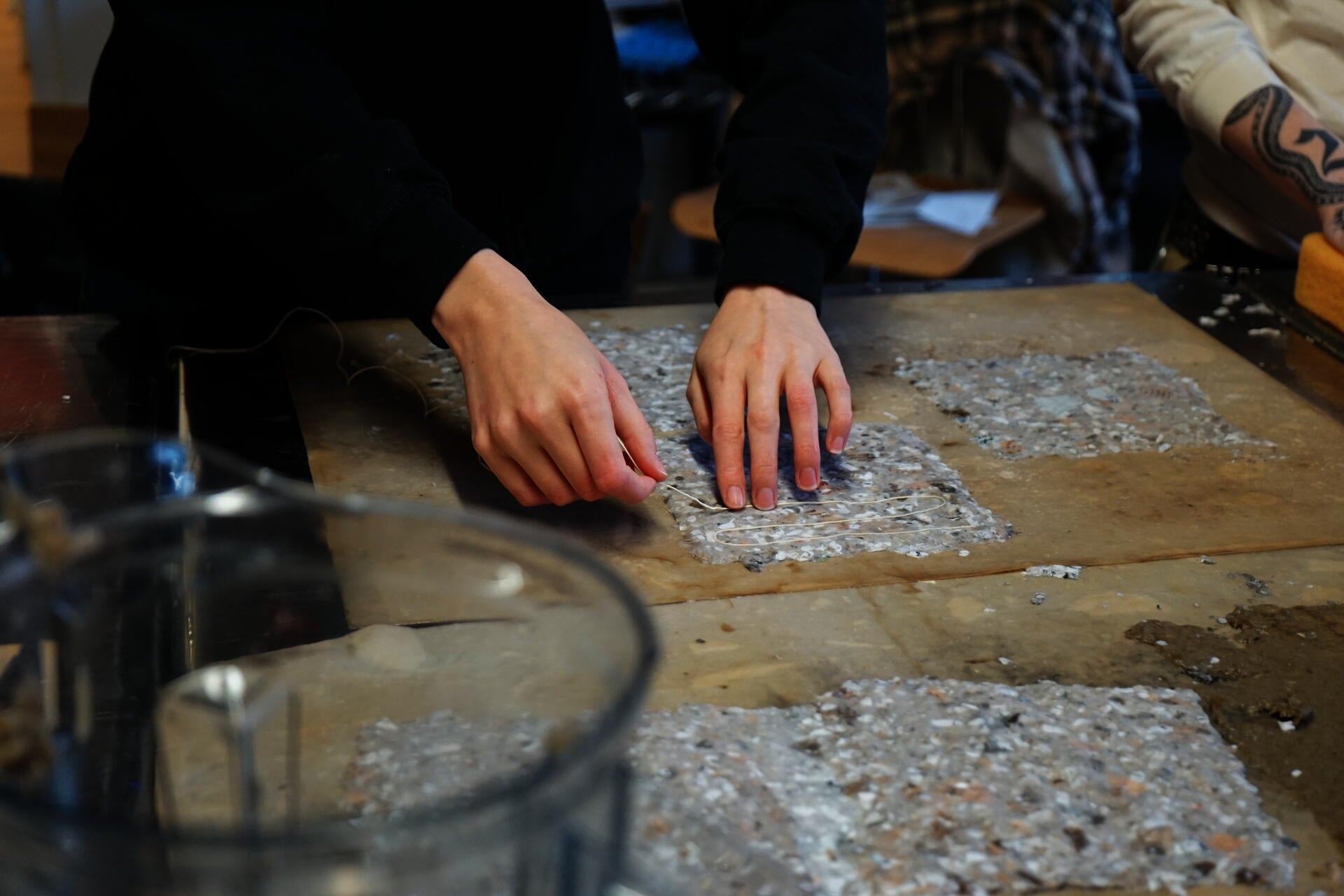 Image of student laying chord on to couched paper pulp. Set in the landscape architecture studio at Weybosset St.
