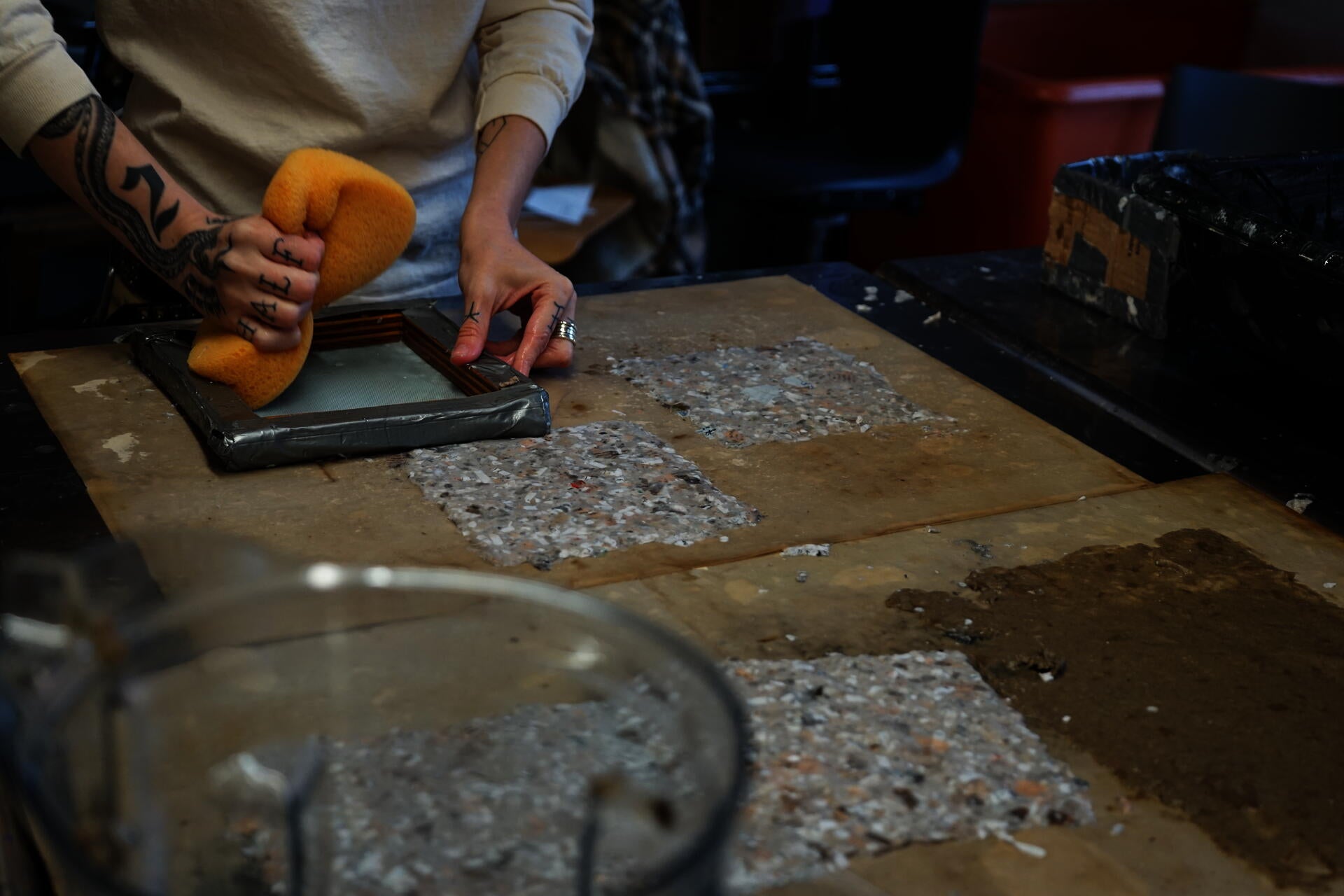 Image of hand holding sponge to absorb water from paper which has just been applied with a deckle.