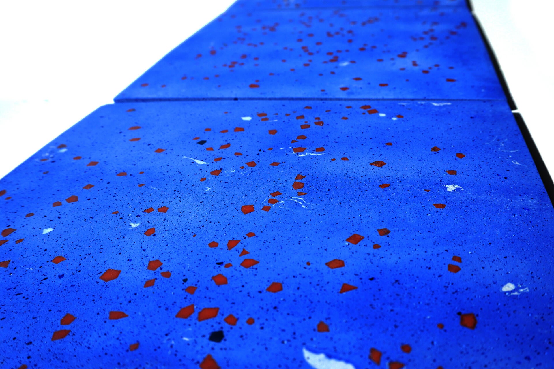 Pale blue terrazzo tiles with scattered geometric fragments seen from a low angle, receding into the distance.