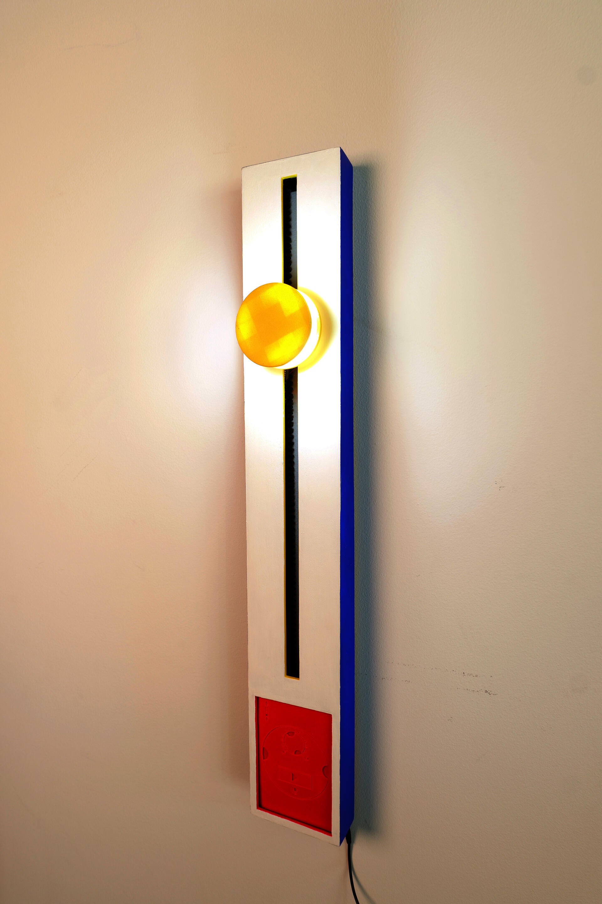 A white and blue vertical rectangle with a yellow cylindrical light, red panel, and blue track.