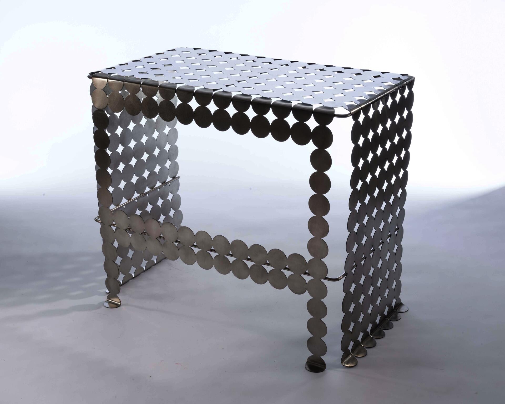 A mirror polished stainless steel vanity table with a circular, gridded pattern. 