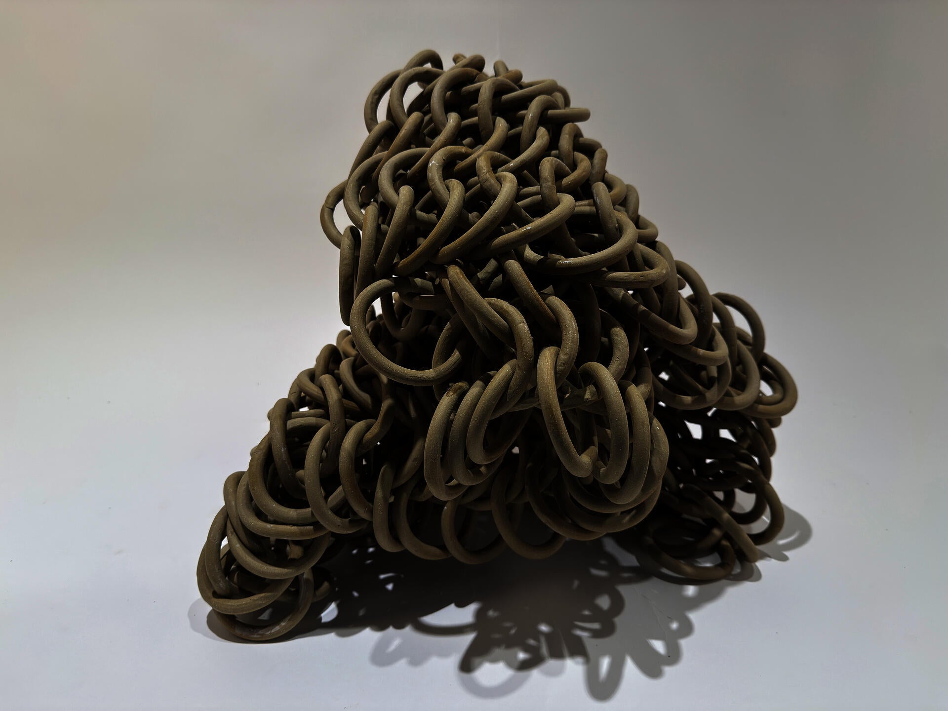 Smooth tan loops form a sheet of heavy chainmail drooping over by its own weight.