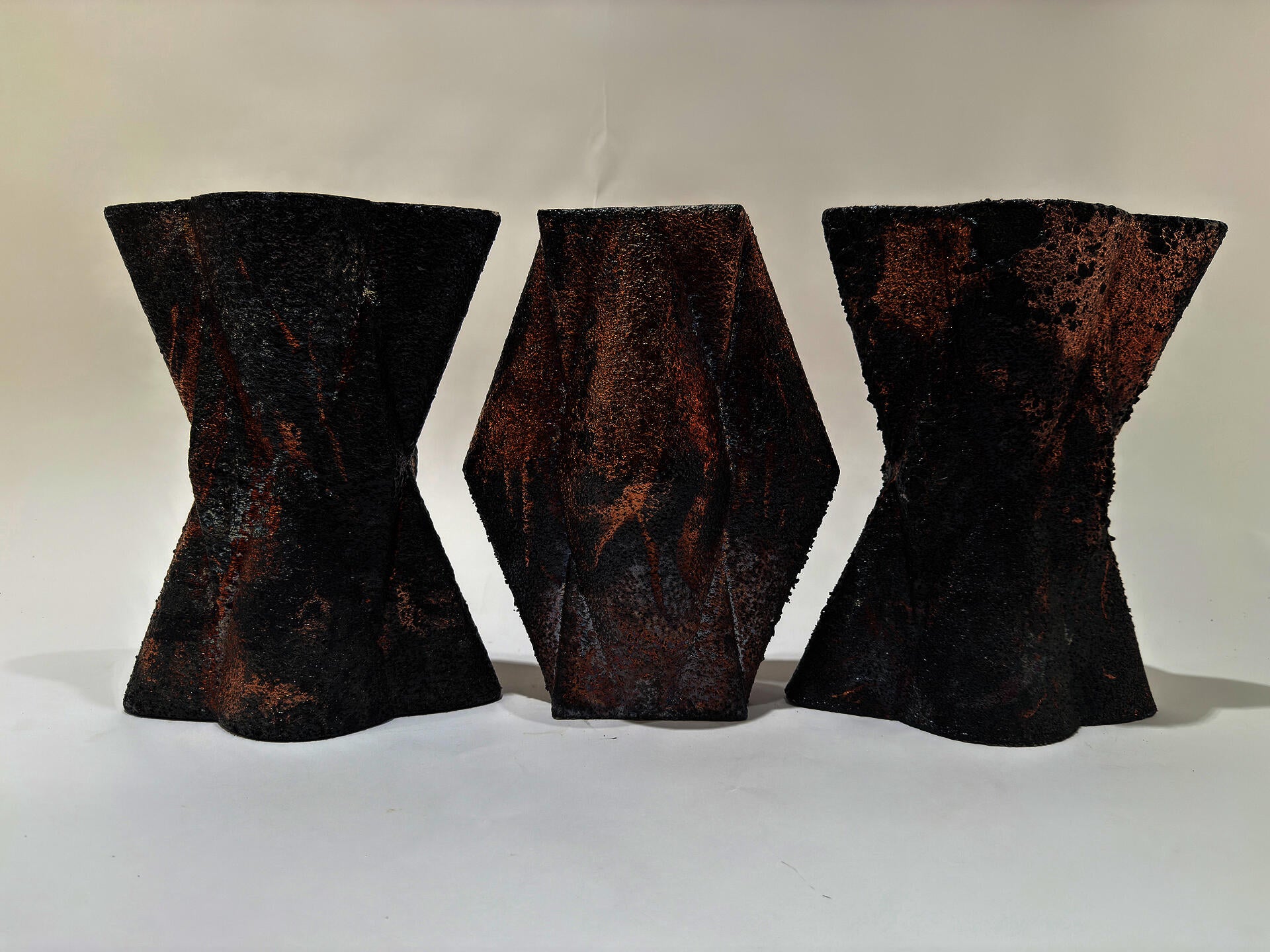 Three shapes of X's and V's align in a row form a pattern.  Their surface is harsh and corse and feels of burnt wood.