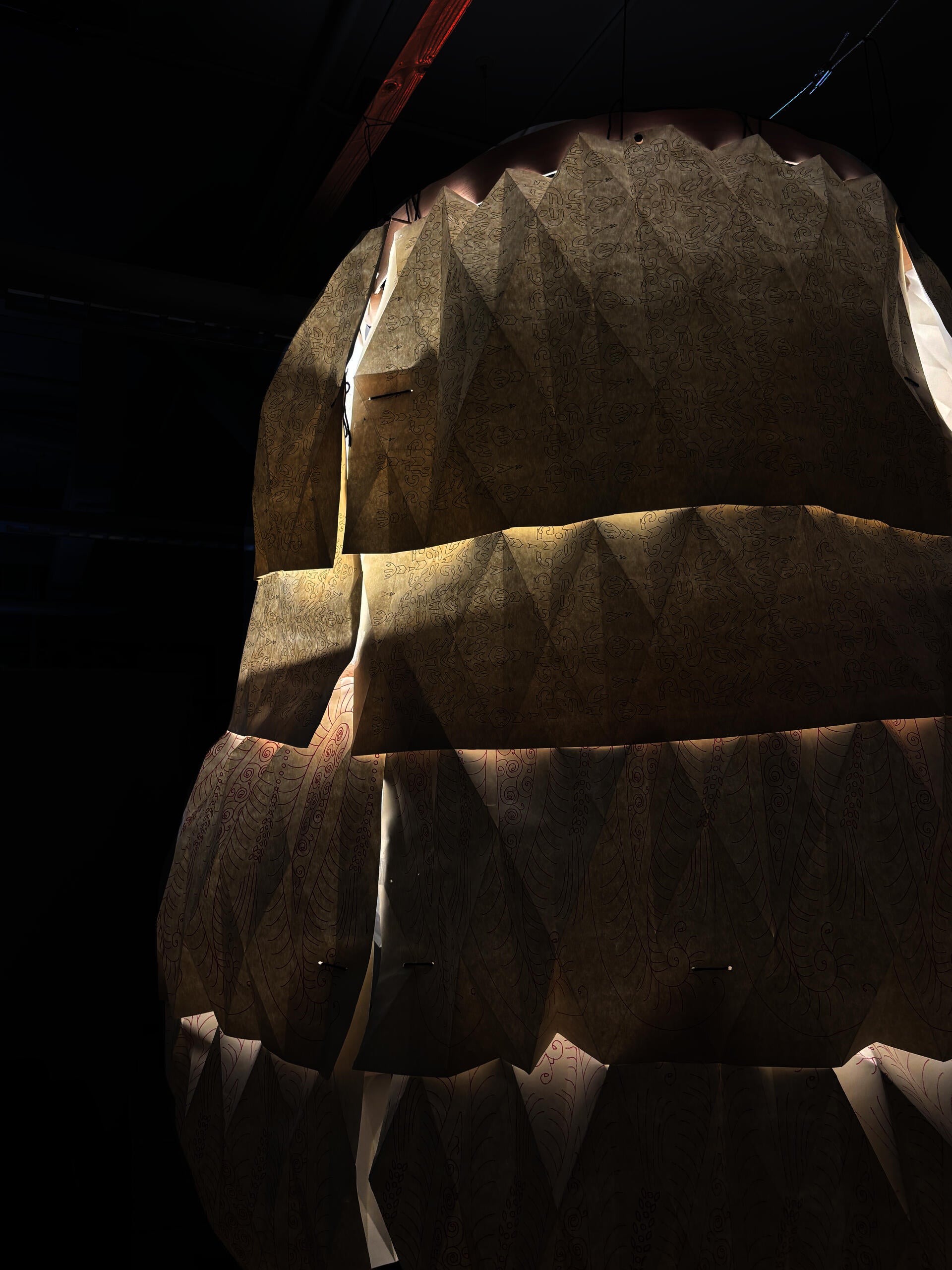 Paper Structure showcasing cascading paper which is layered and hung from the ceiling. Each page features textile designs that have been drawn onto the surface of the sheets.