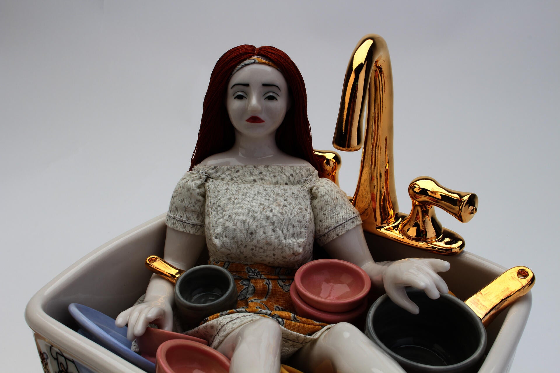 a sad doll sitting in a sink filled with colorful dishes, illustrated with a dining room scene and floral decoration