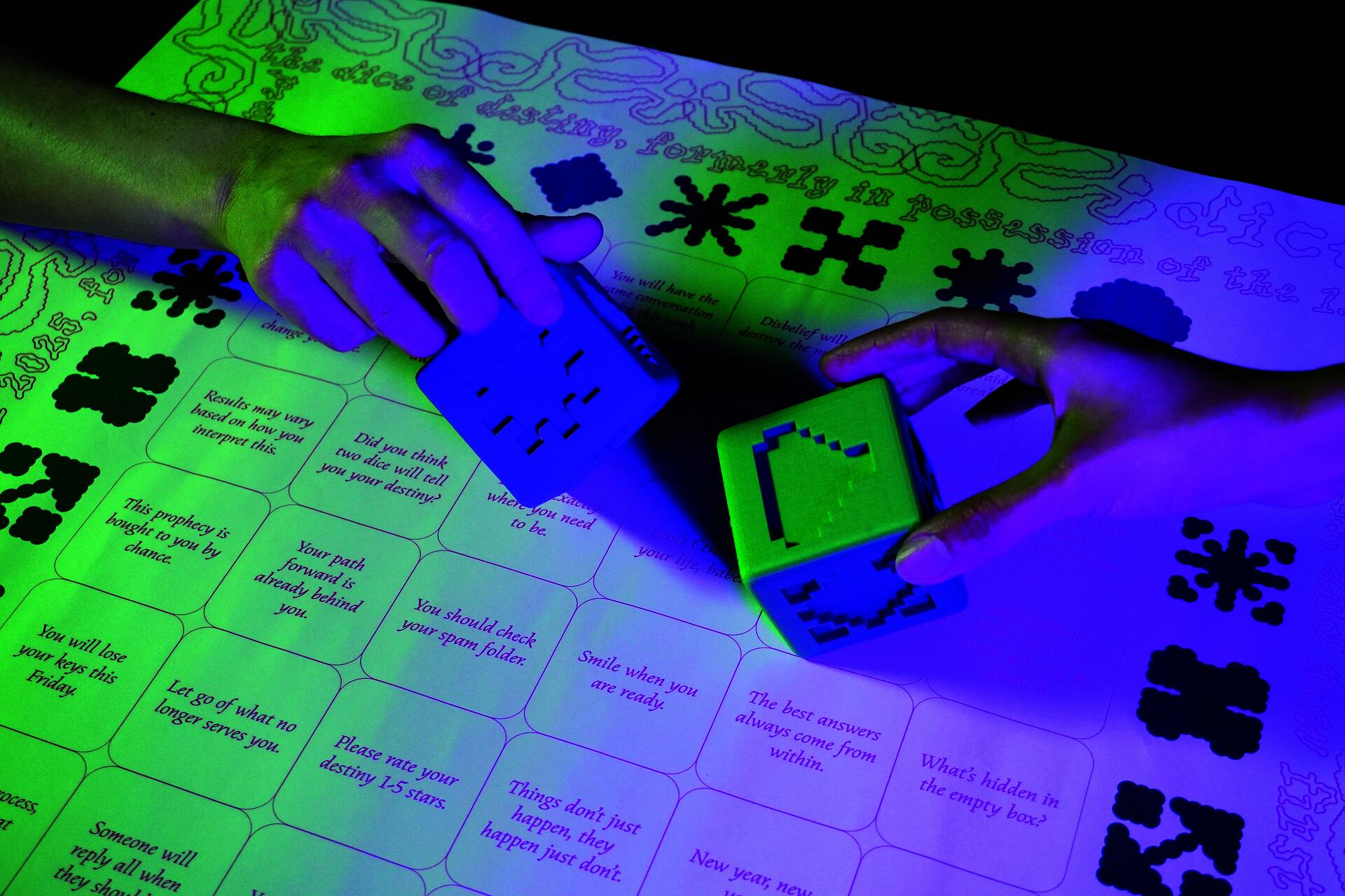 Two glowing dice with abstract symbols rest on a fortune-telling chart, their faces illuminated in vibrant green, blue, and purple against text containing 36 mystical fortunes exploring chance and meaning-making.