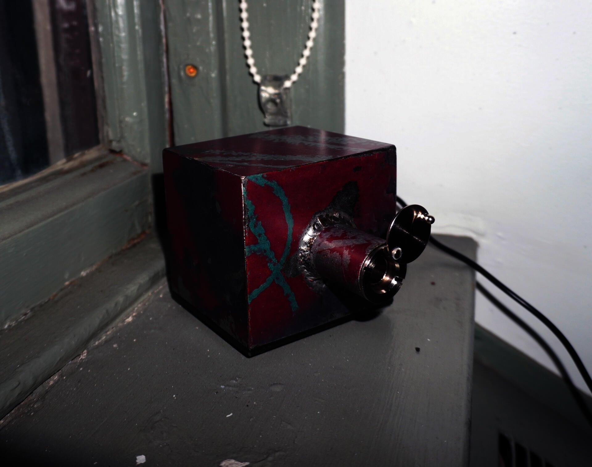 An alarm clock locked inside of a small metal box, that can only be viewed through a peephole.