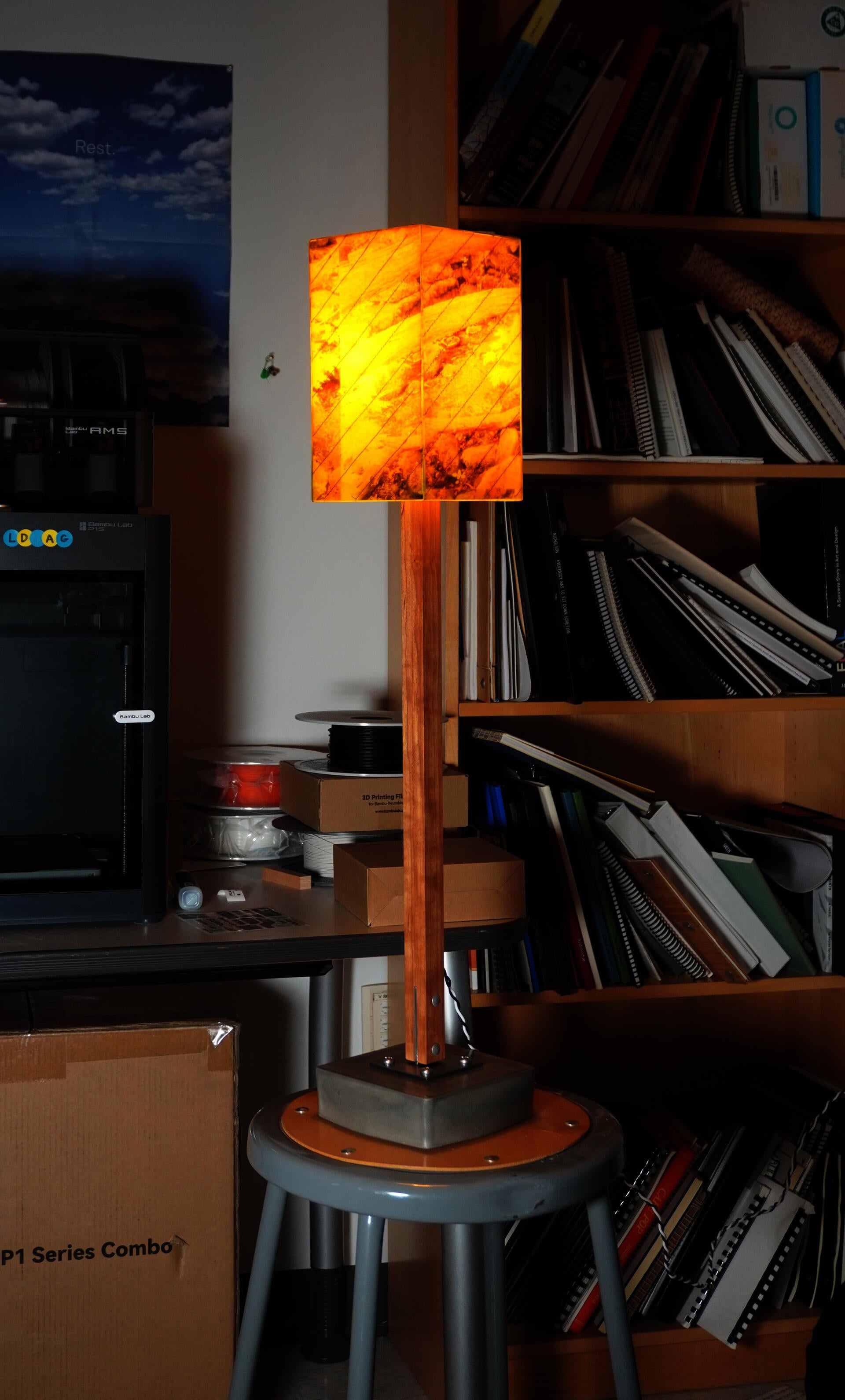 A fiberglass box with images of the forest is supported by post made of cherry wood and is attached to a small concrete pad with a semi architectural T-connector