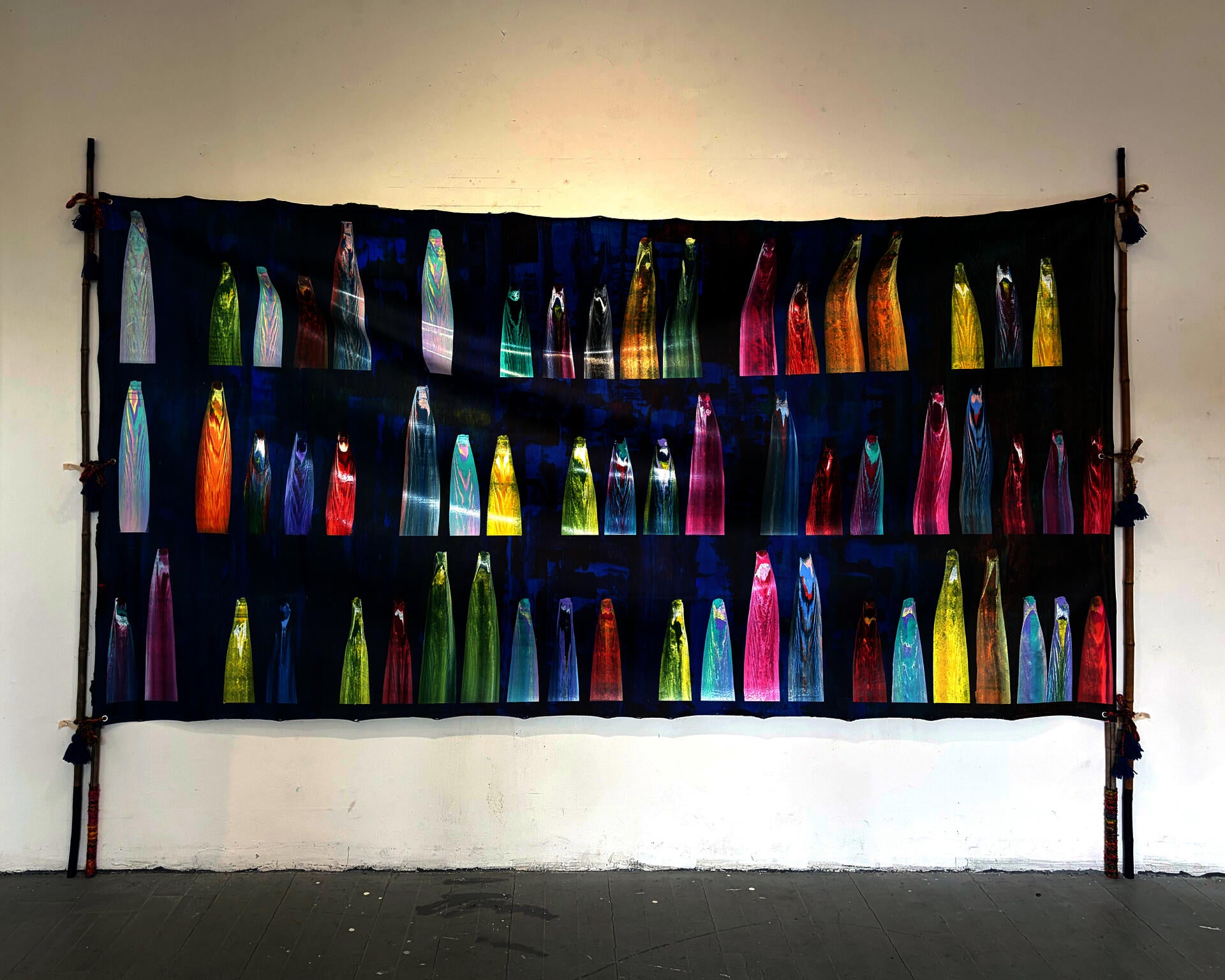 Its a Blue panel, hung through bamboos and ropes. Represents wedding tent structure from South Asia, there are multicolor gestural marks, that personal text in a coded language. 