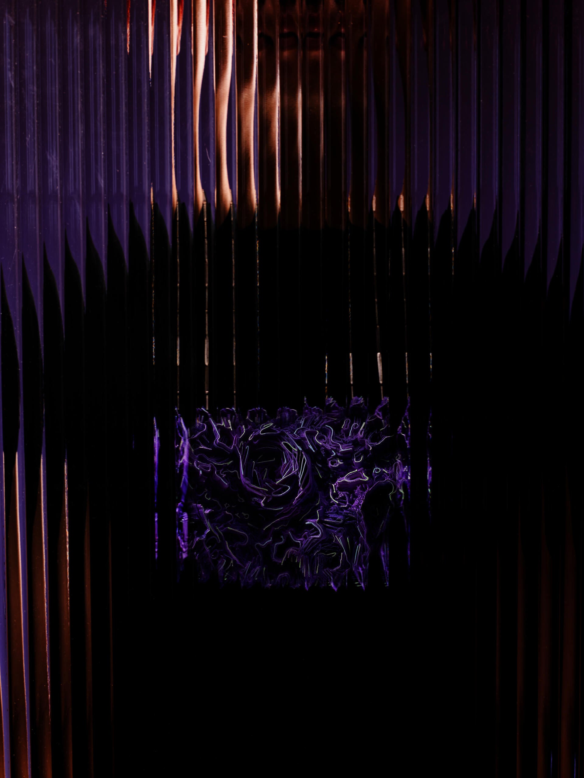 Curved purple necklace with a dense surface of small wall-like forms rising and falling, hanging from a thin silver chain.