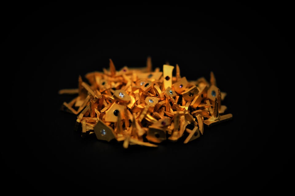 Photograph of a pile of small gold nails with diamonds