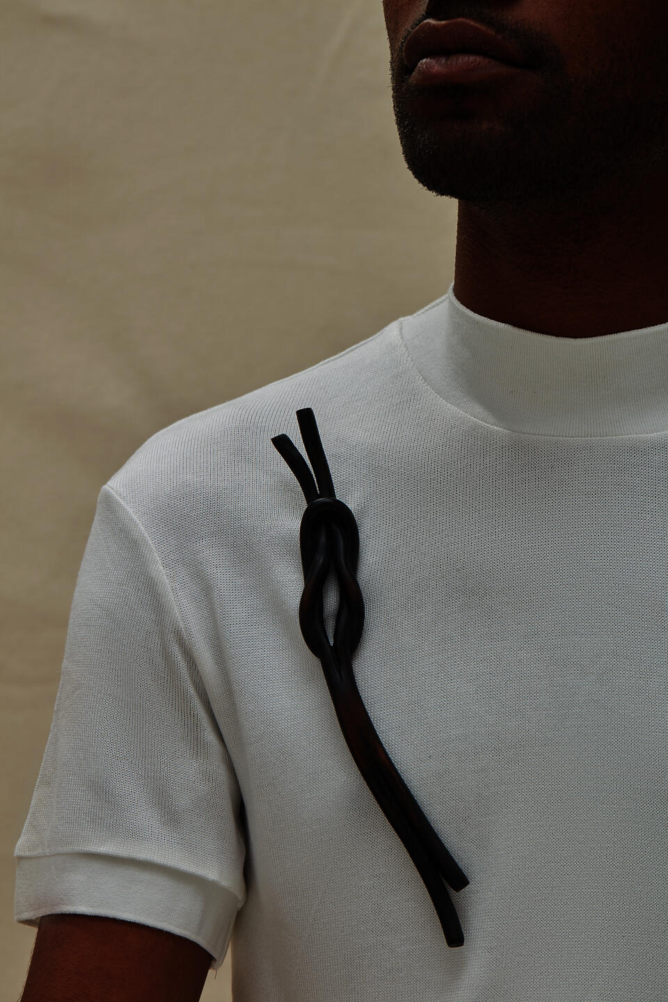 A dark knot brooch carved from wood, worn by a model