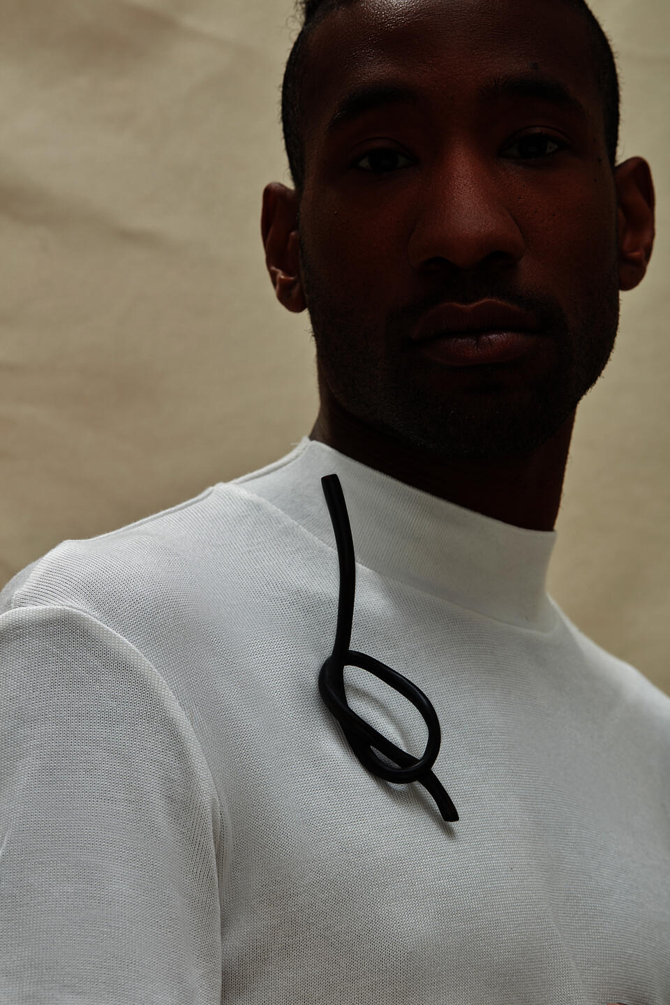 A dark knot brooch carved from wood, worn by a model