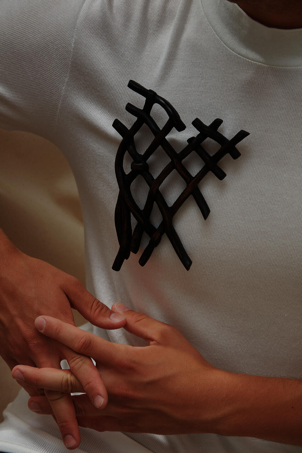 A dark knot brooch carved from wood, worn by a model