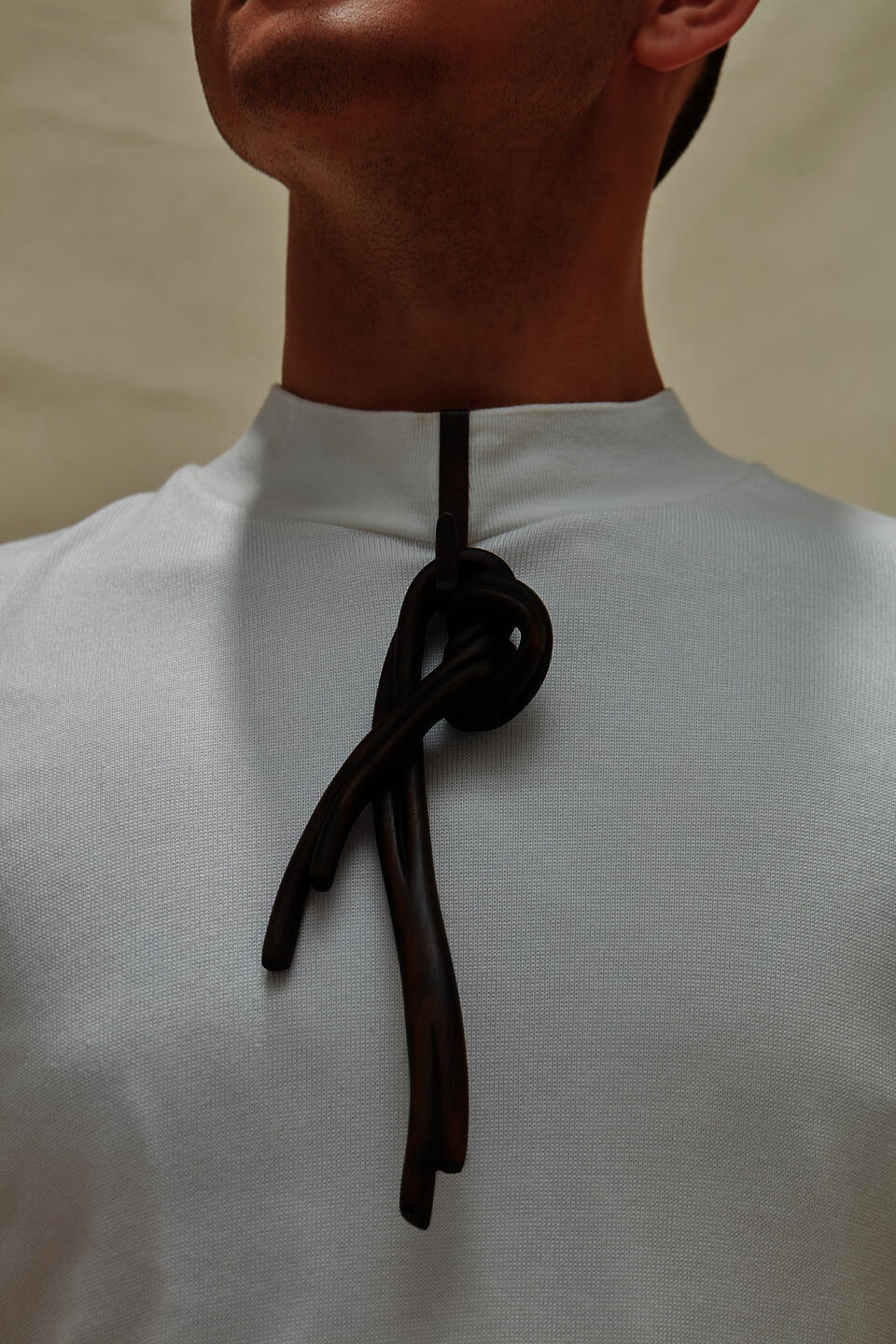 A dark knot brooch carved from wood, worn by a model