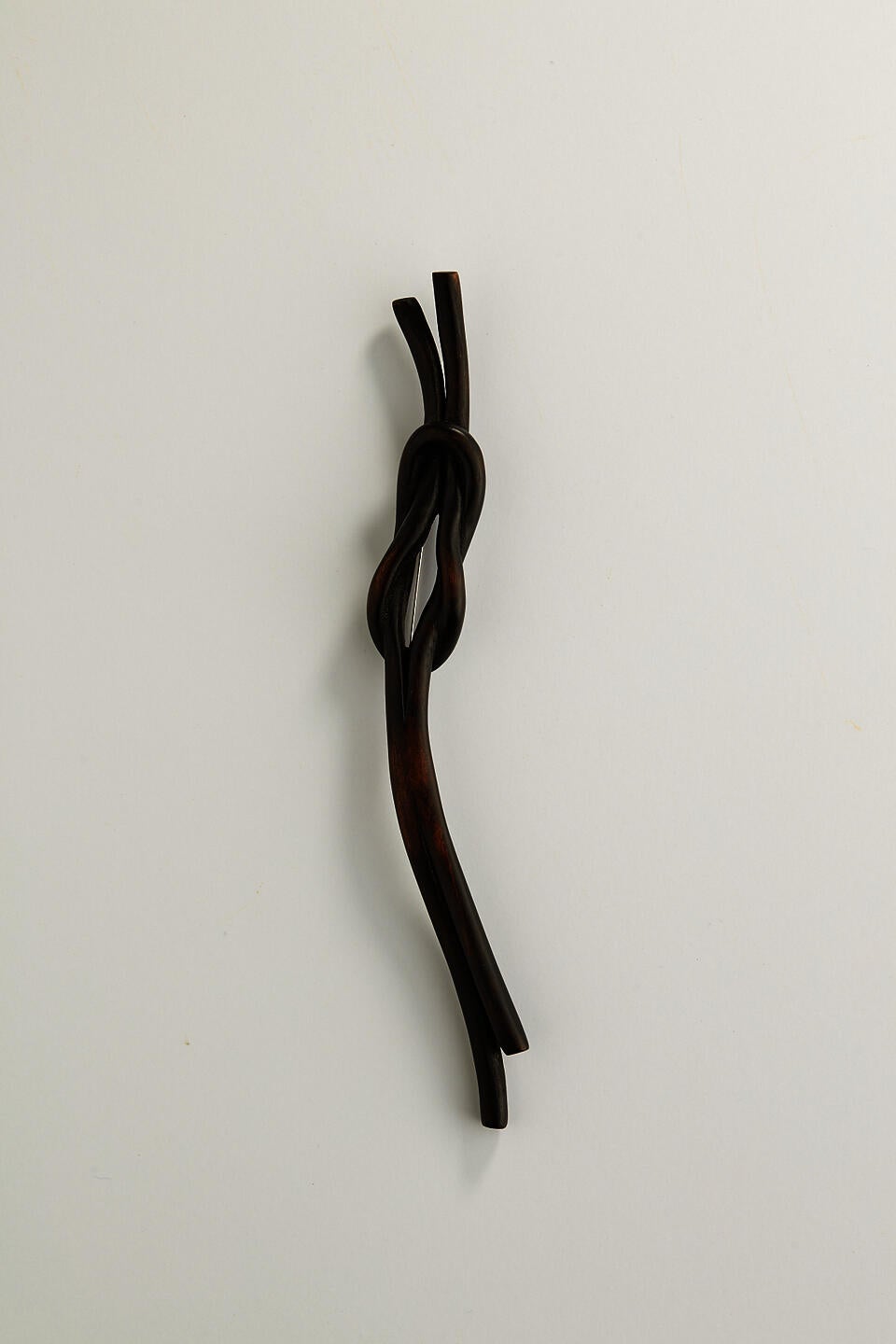A dark knot brooch carved from wood