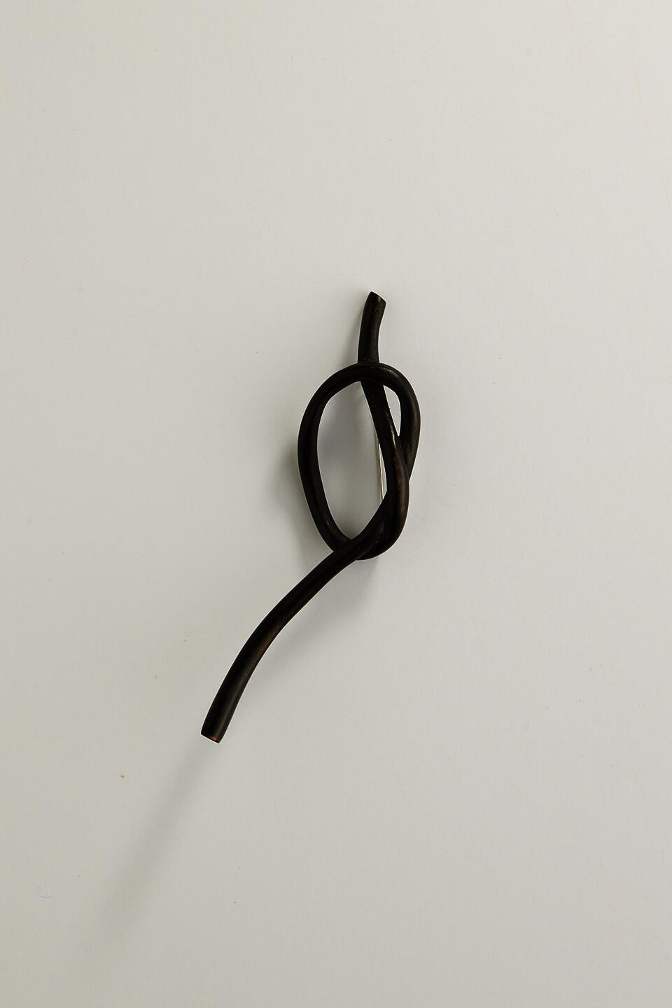 A dark knot brooch carved from wood