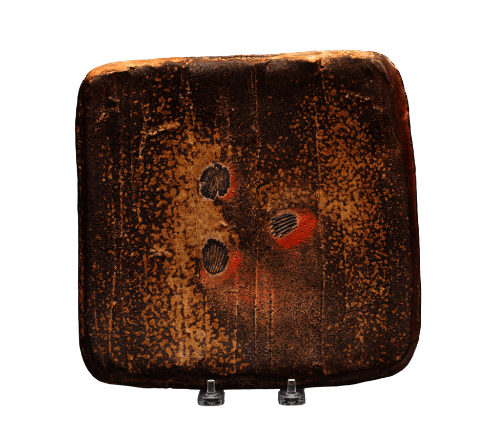 Brown square plate with tan splatters. In the center, three indentations in the shape of shellsare surrounded by red marks