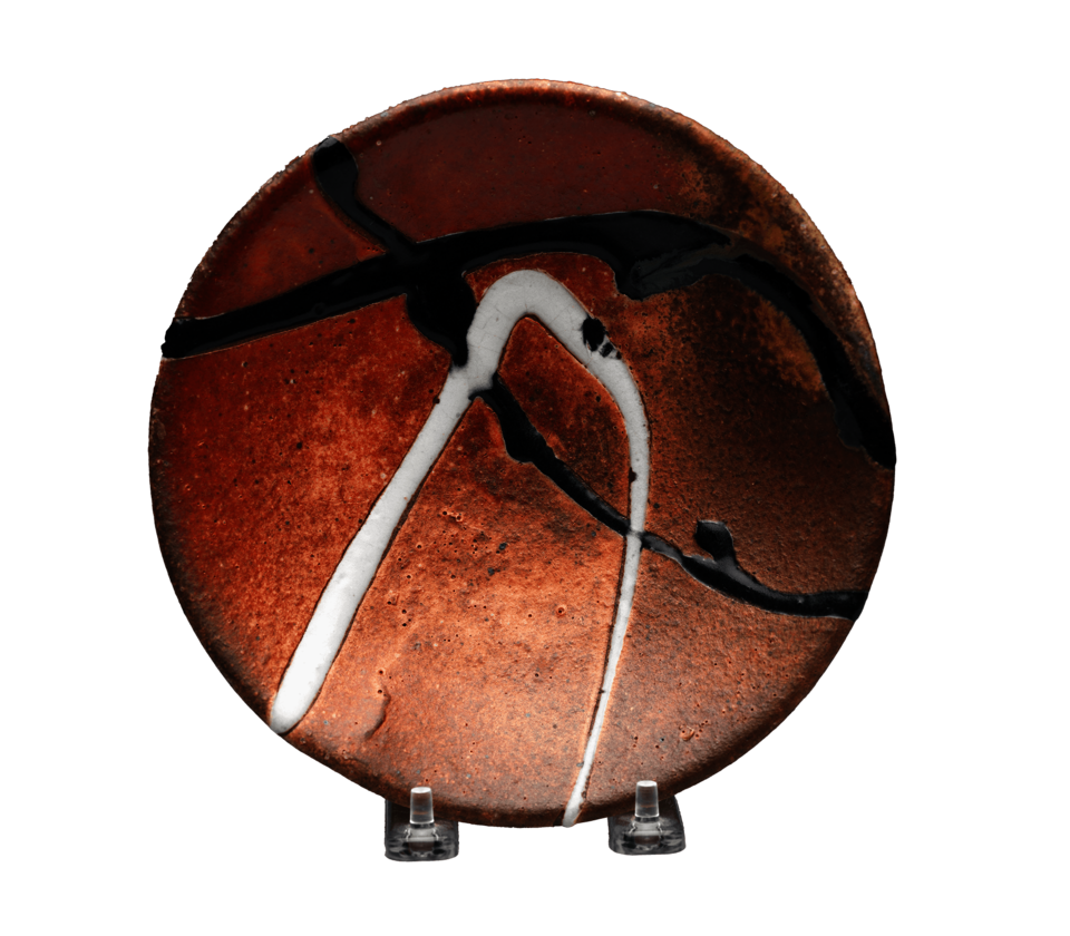 A rust-colored circular plate with splashes of white and black.